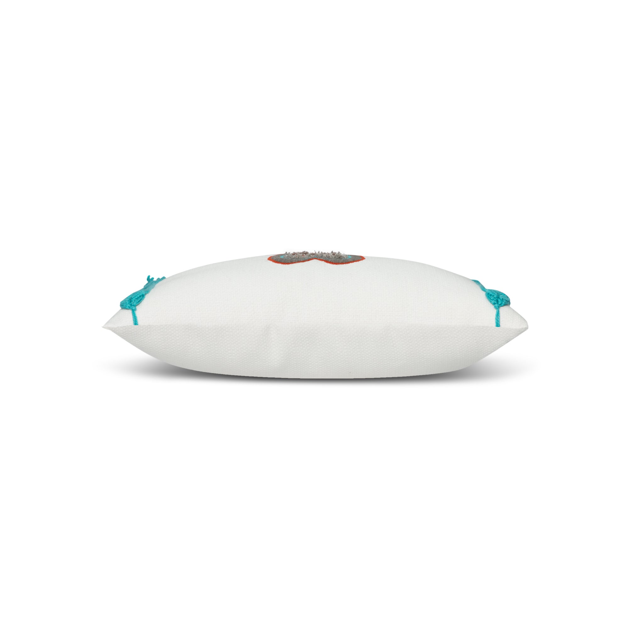 Side image of White pillow with cut out heart in red and gray and aruba tassels in western theme.