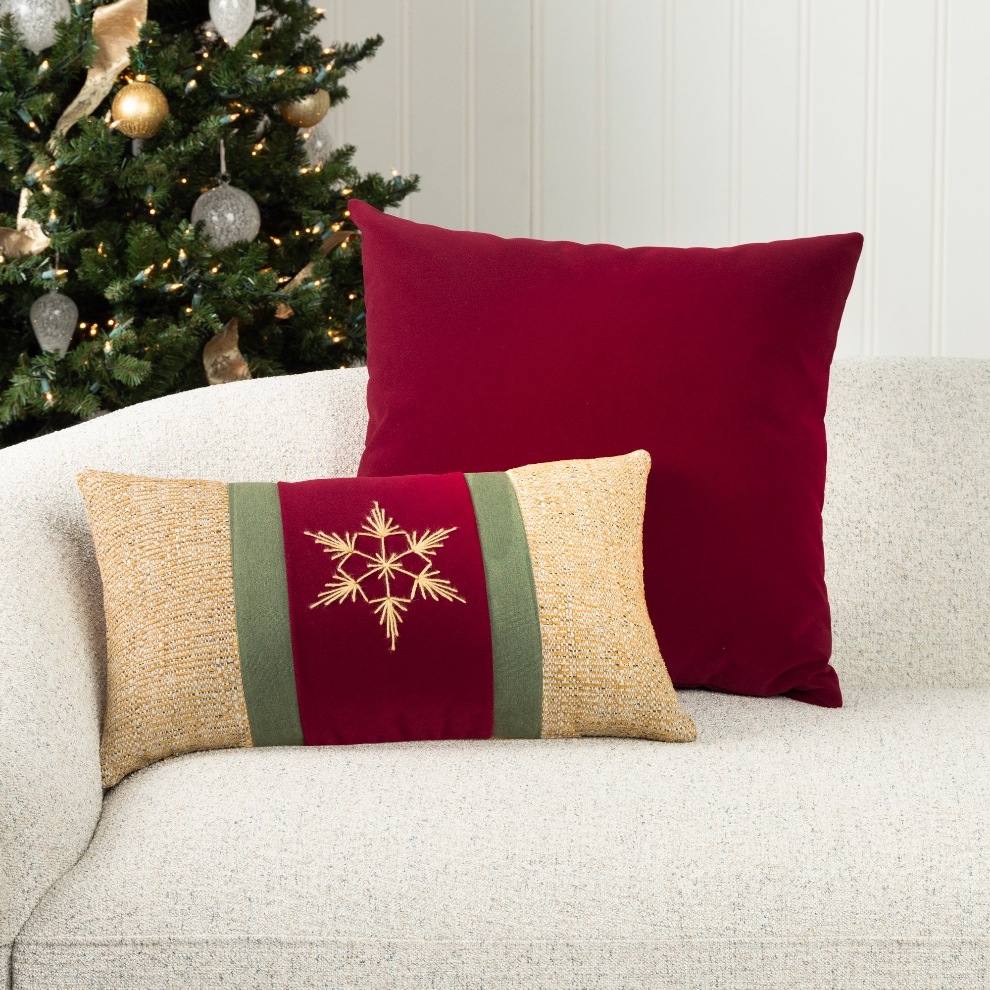 Indoor environmental image of ruby red velvet pillow and holiday lumbar in red and gold with hand stitched snowflake detail on ivory sofa