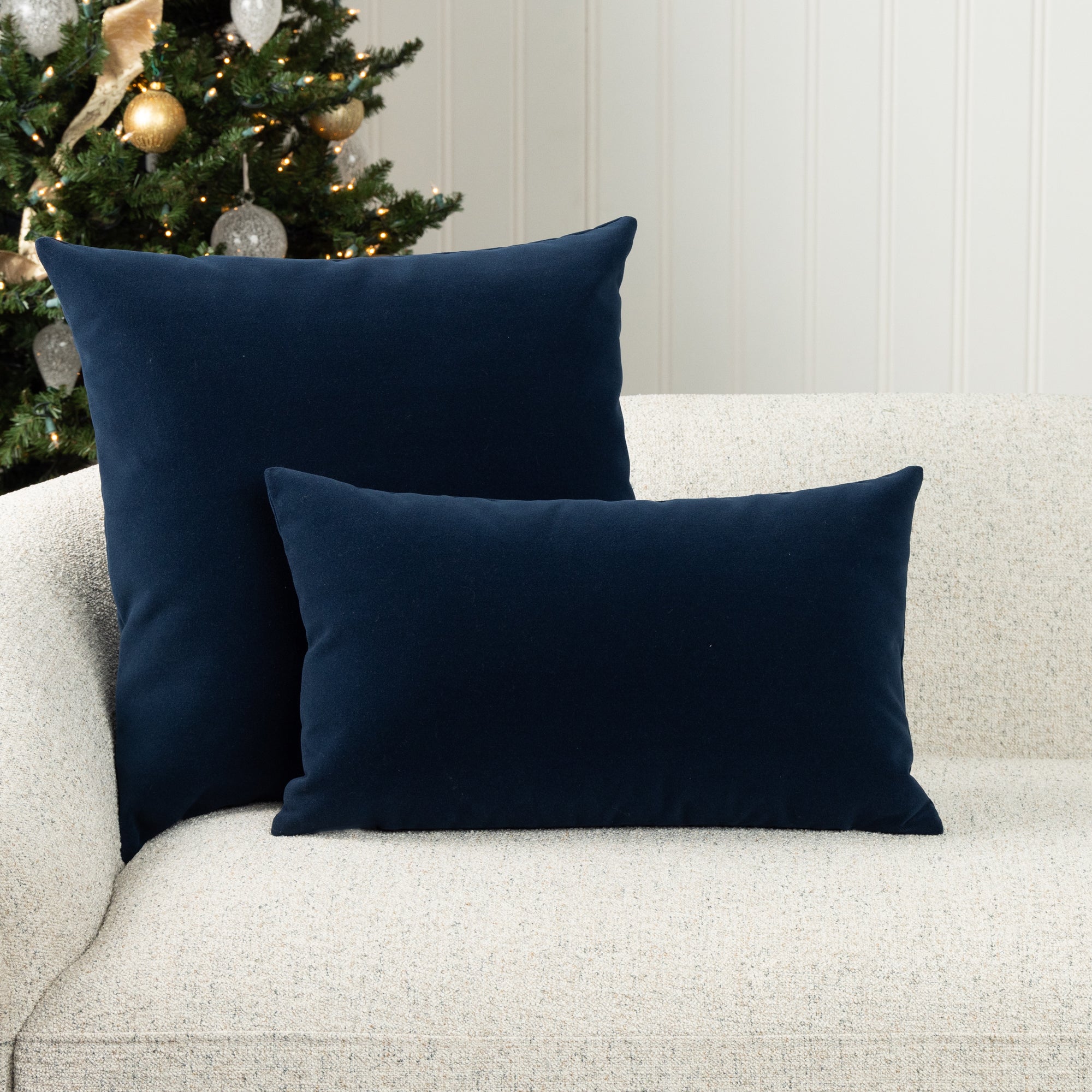 Two velvet pillows in midnight blue on ivory sofa, outdoor safe woven textile