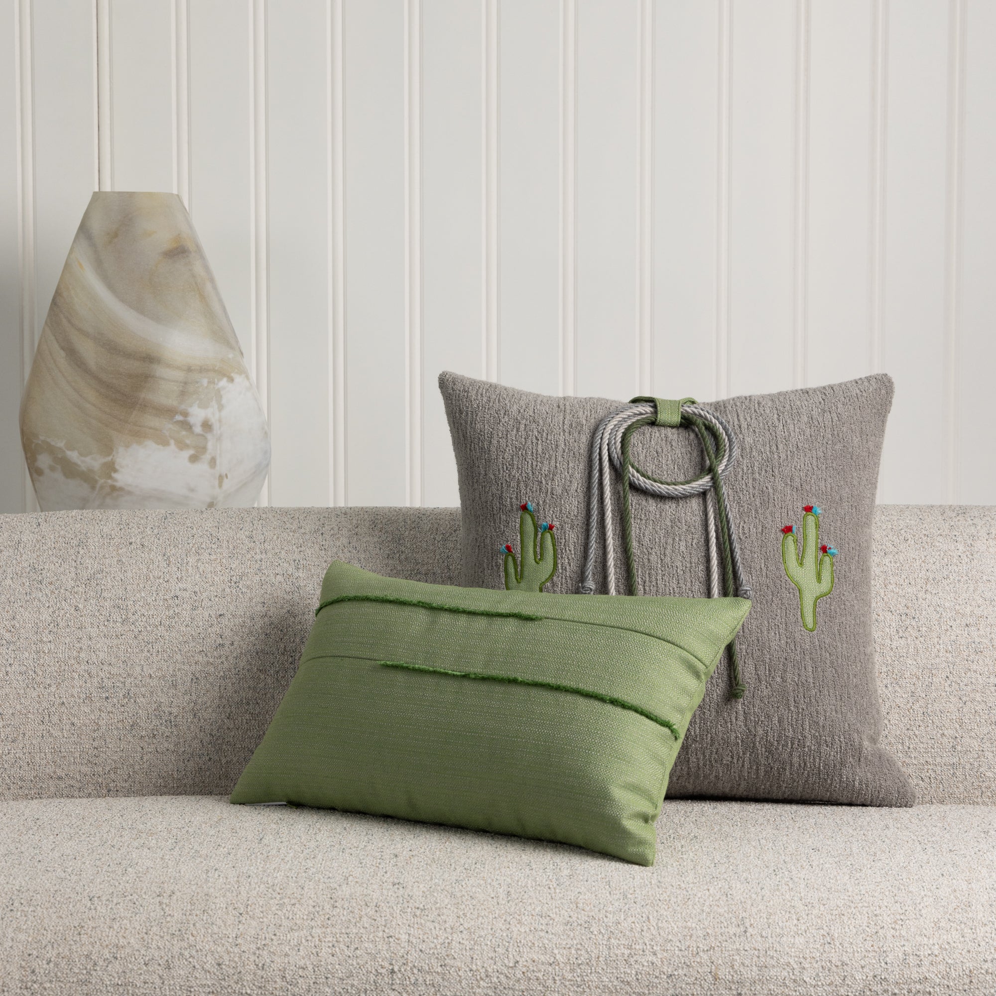 Indoor image of western themed accent pillow in gray with green lumbar on ivory sofa