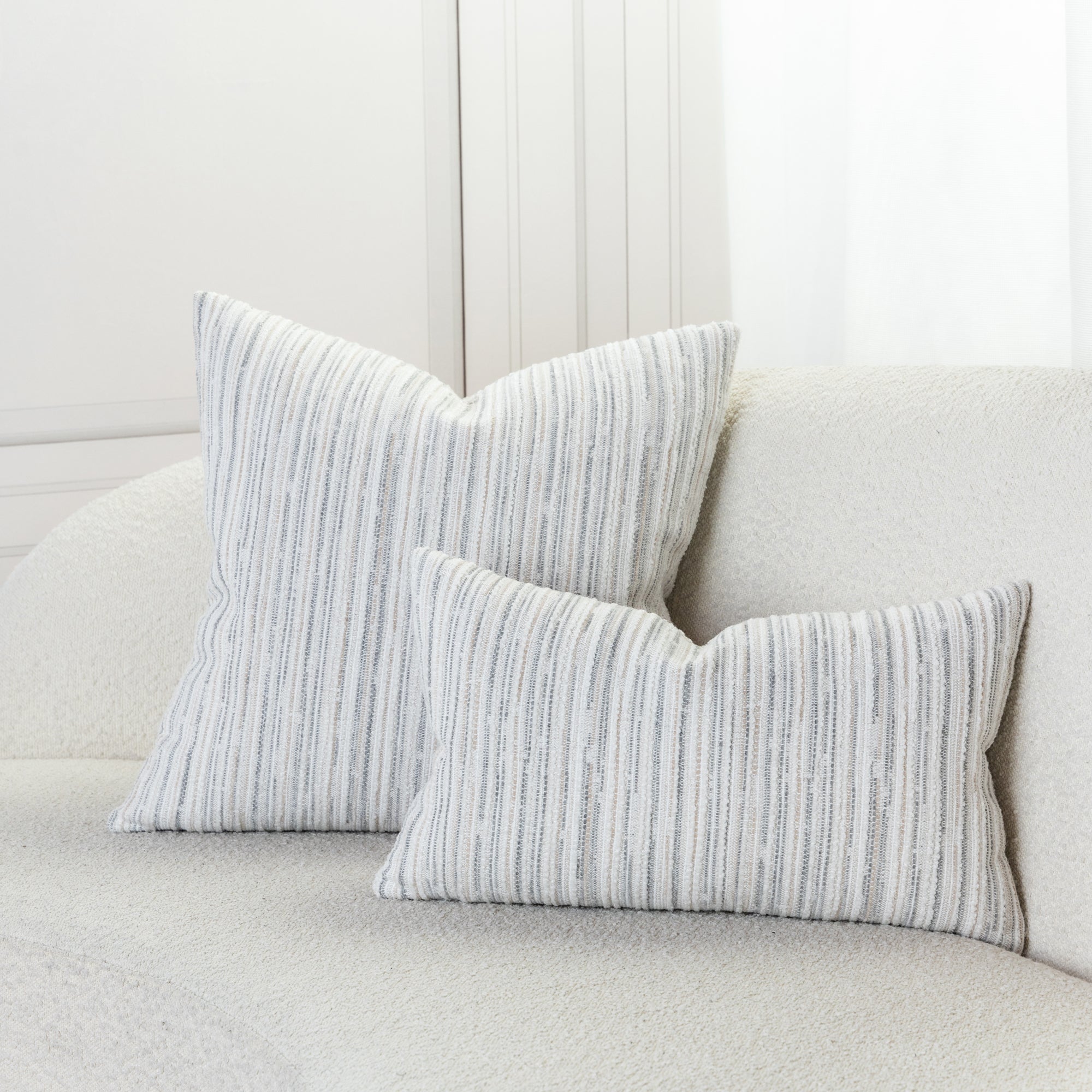 Indoor environmental image of pillows in Outdoor-safe fabric with narrow vertical stripes in soft pebble hues of soft chenille