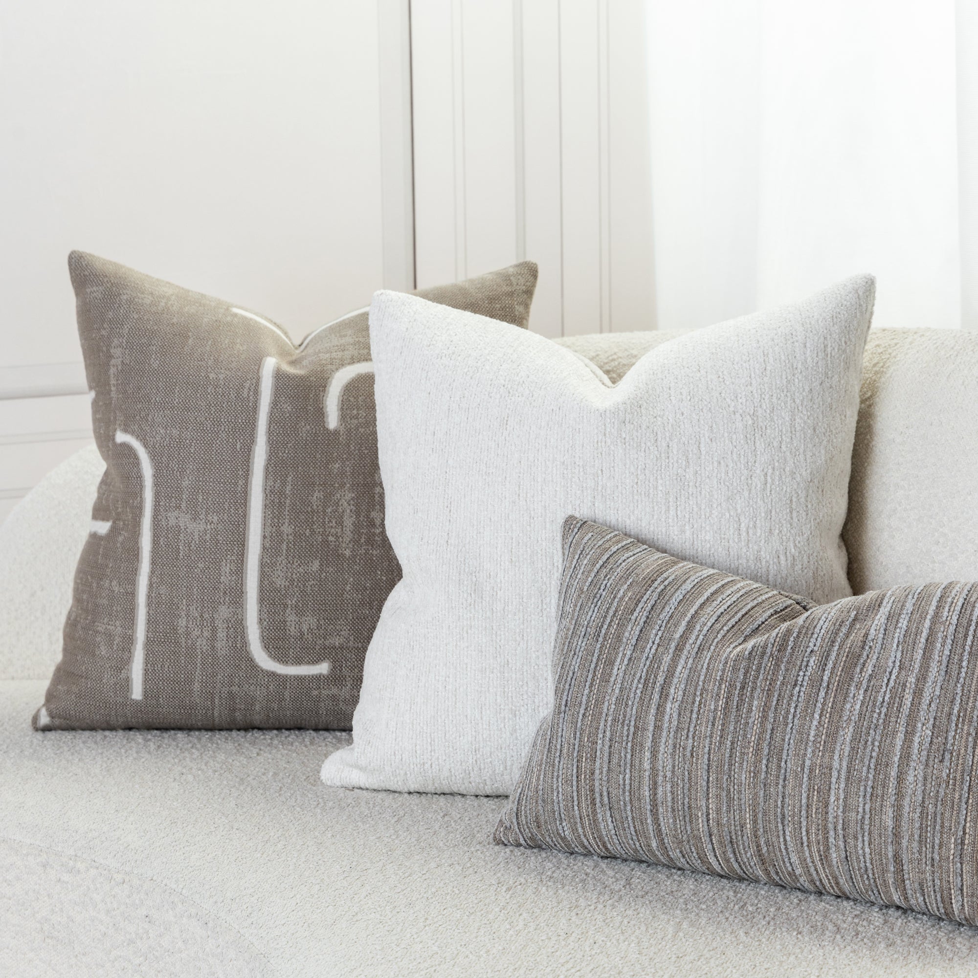 Indoor environmental image of pillows in Taupe outdoor-safe fabric with abstract white linear design