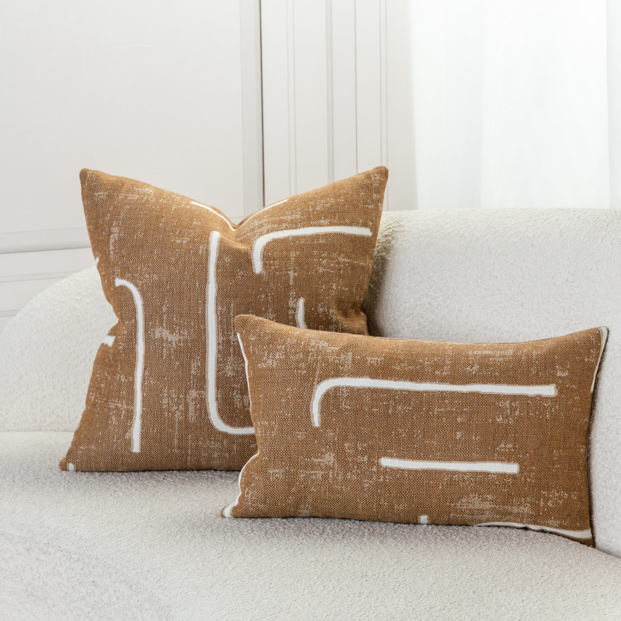 Abstract patterned pillows in caramel on ivory sofa, safe for outdoor and indoor use 