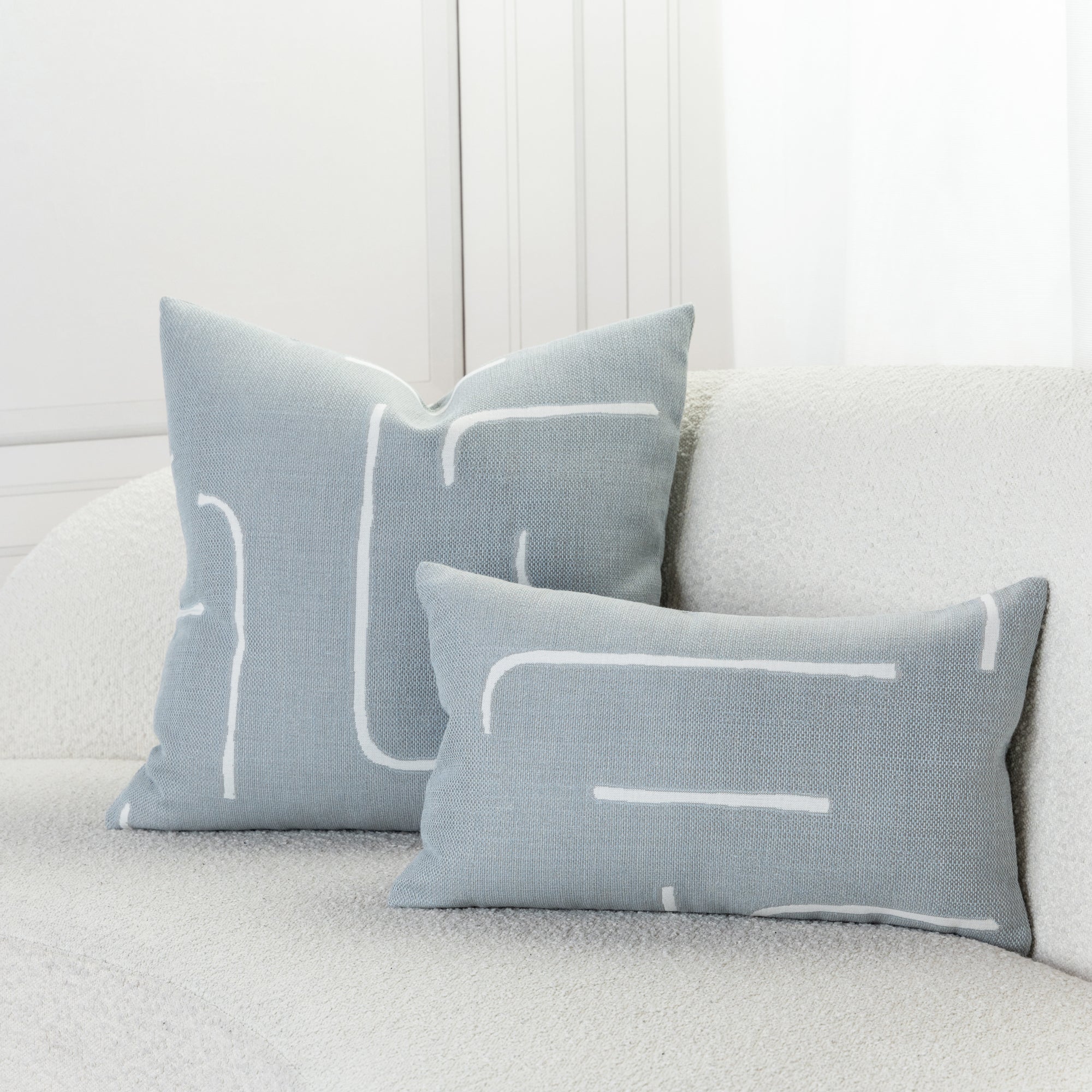 Indoor environmental image of pillows in Soft blue outdoor safe woven fabric with abstract linear design
