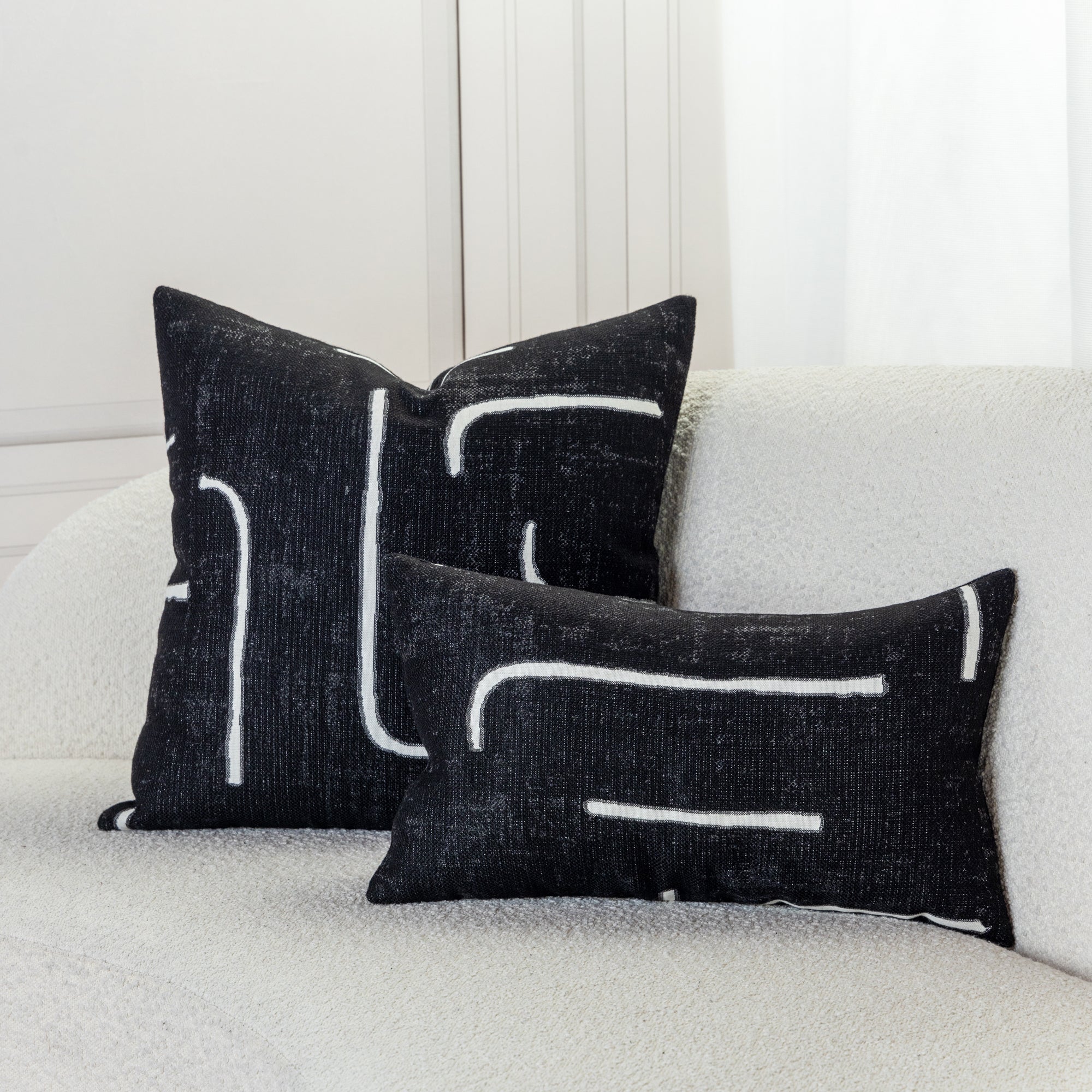 Abstract patterned pillows in black on ivory sofa, safe for outdoor and indoor use 