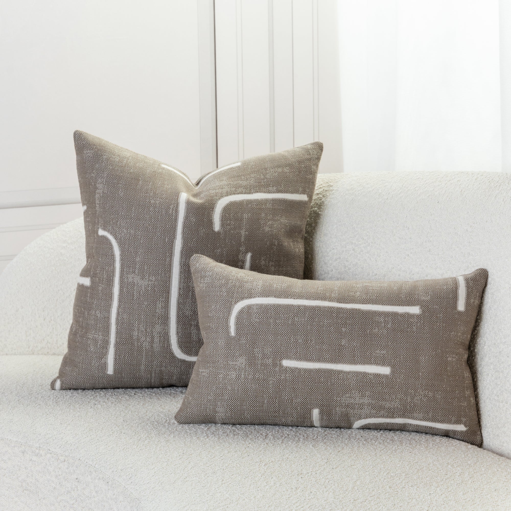 Abstract patterned pillows in taupe on ivory sofa, safe for outdoor and indoor use 