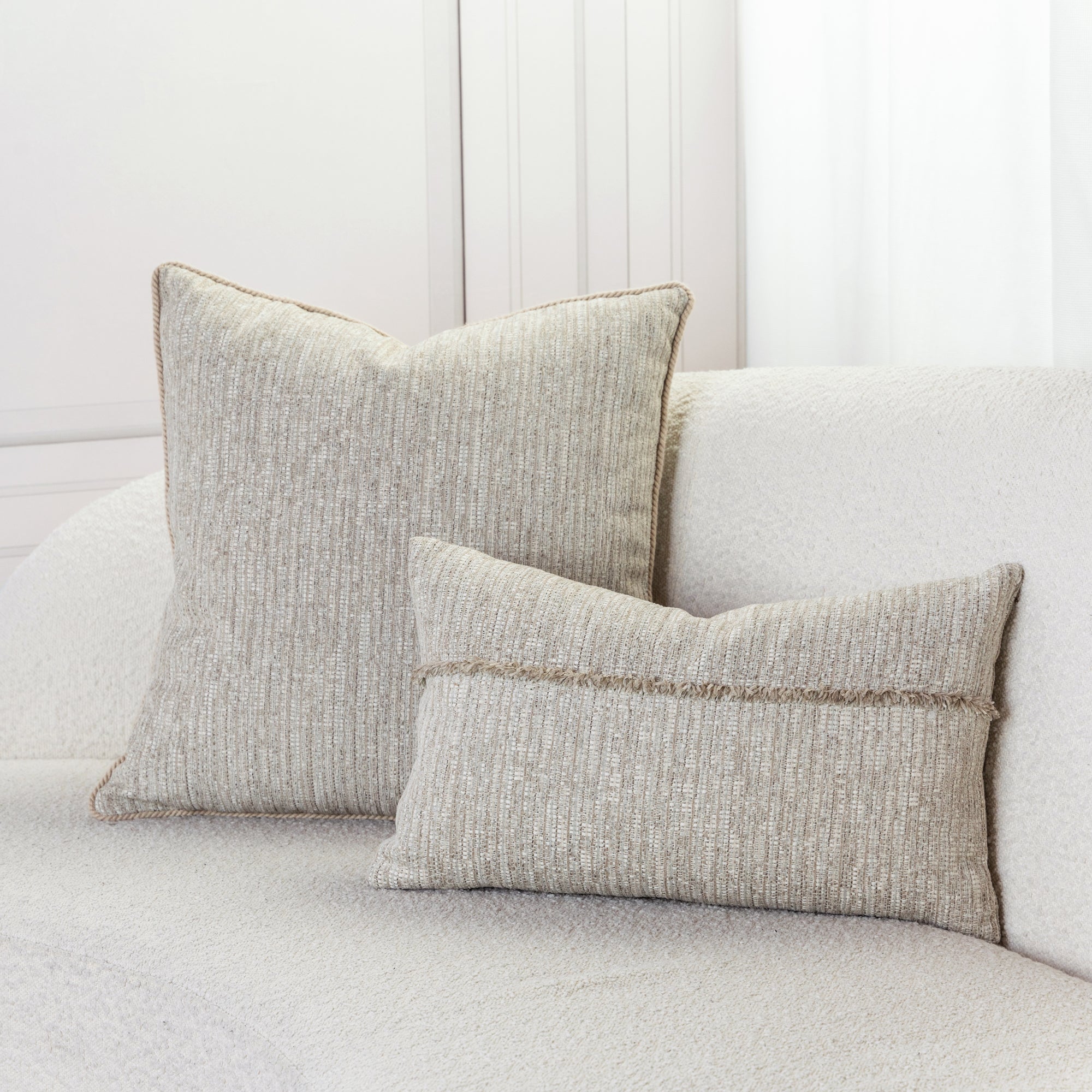 Indoor environmental image of pillows in Warm fawn-colored outdoor-safe fabric with textured luxury weave and chenille accents