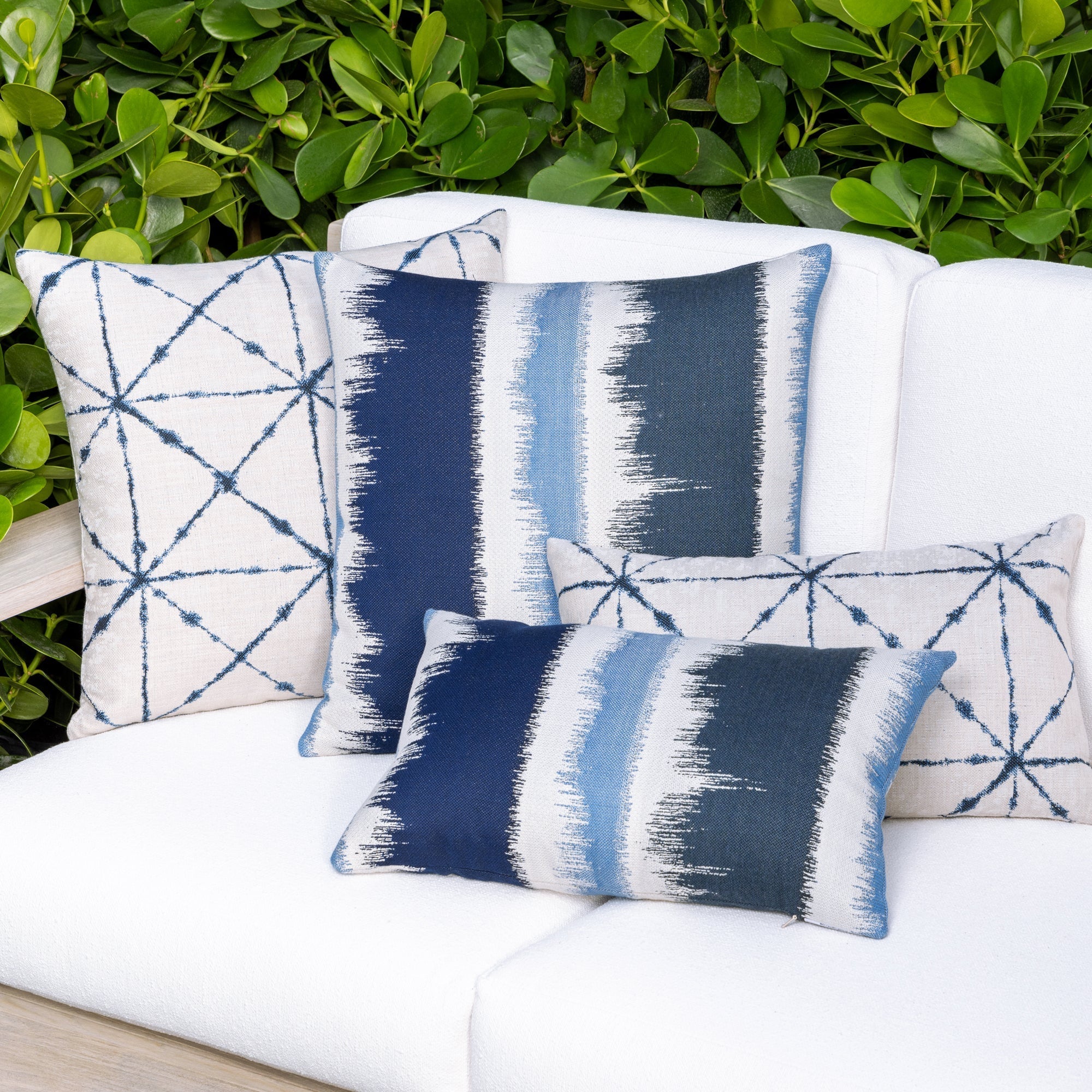Outdoor image of group of pillows in indigo in variety of patterns, all are outdoor safe