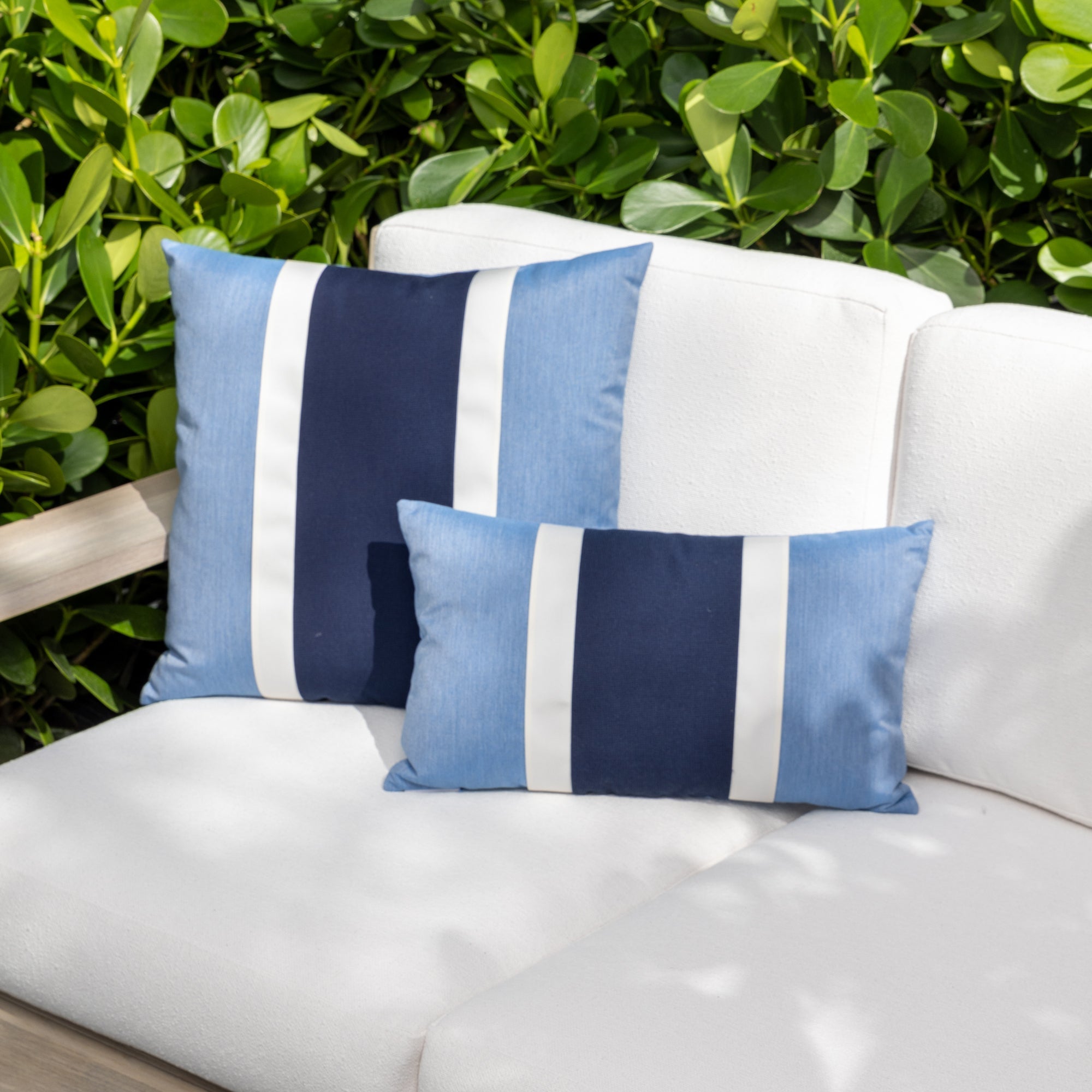Luxury blue and white solid throw pillow on a woven lounge chair, featuring UV and fade resistant fabric to complete indoor and outdoor decor