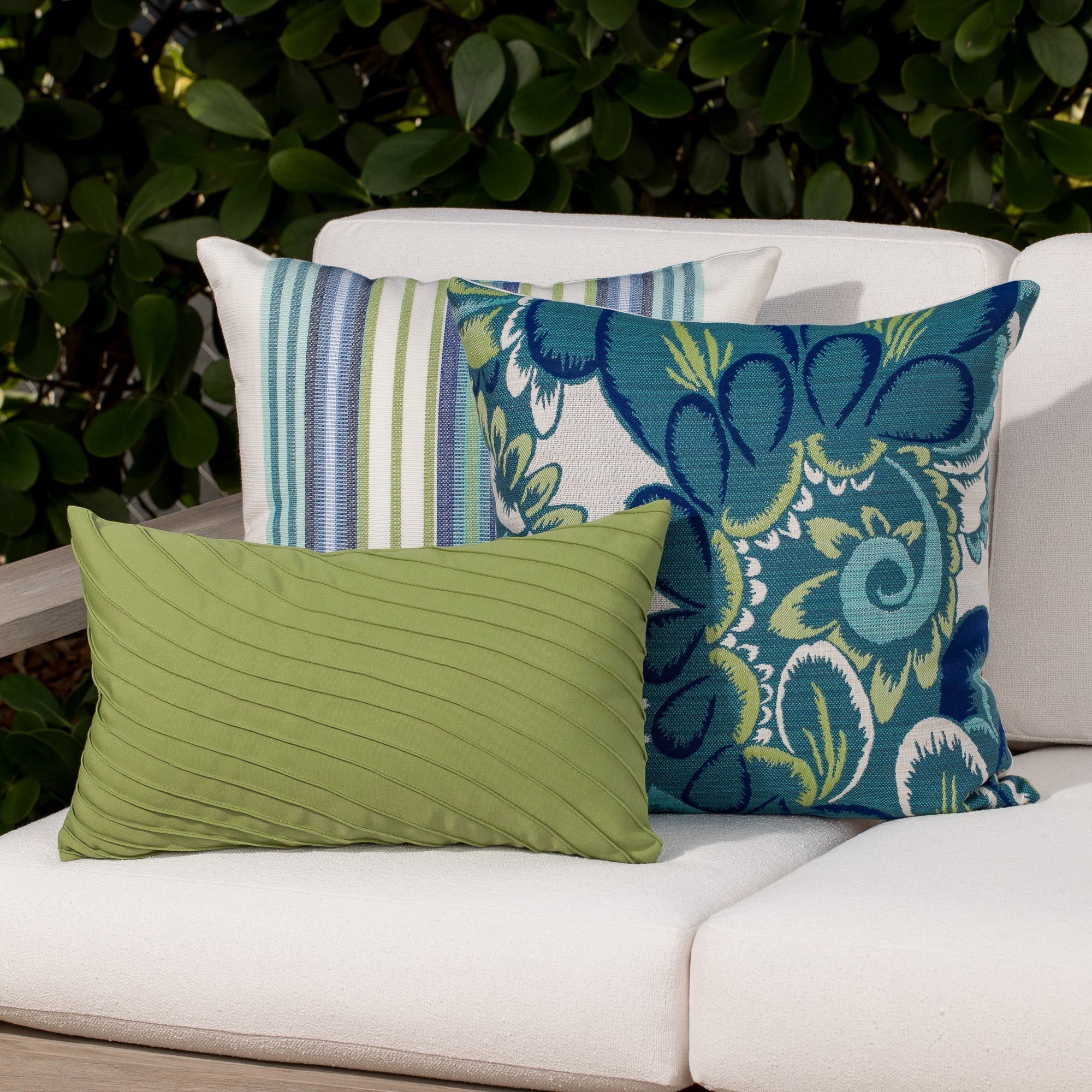 Luxury green textured woven and floral pillows on a outdoor sofa, featuring all weather performance construction for residential and commercial interiors