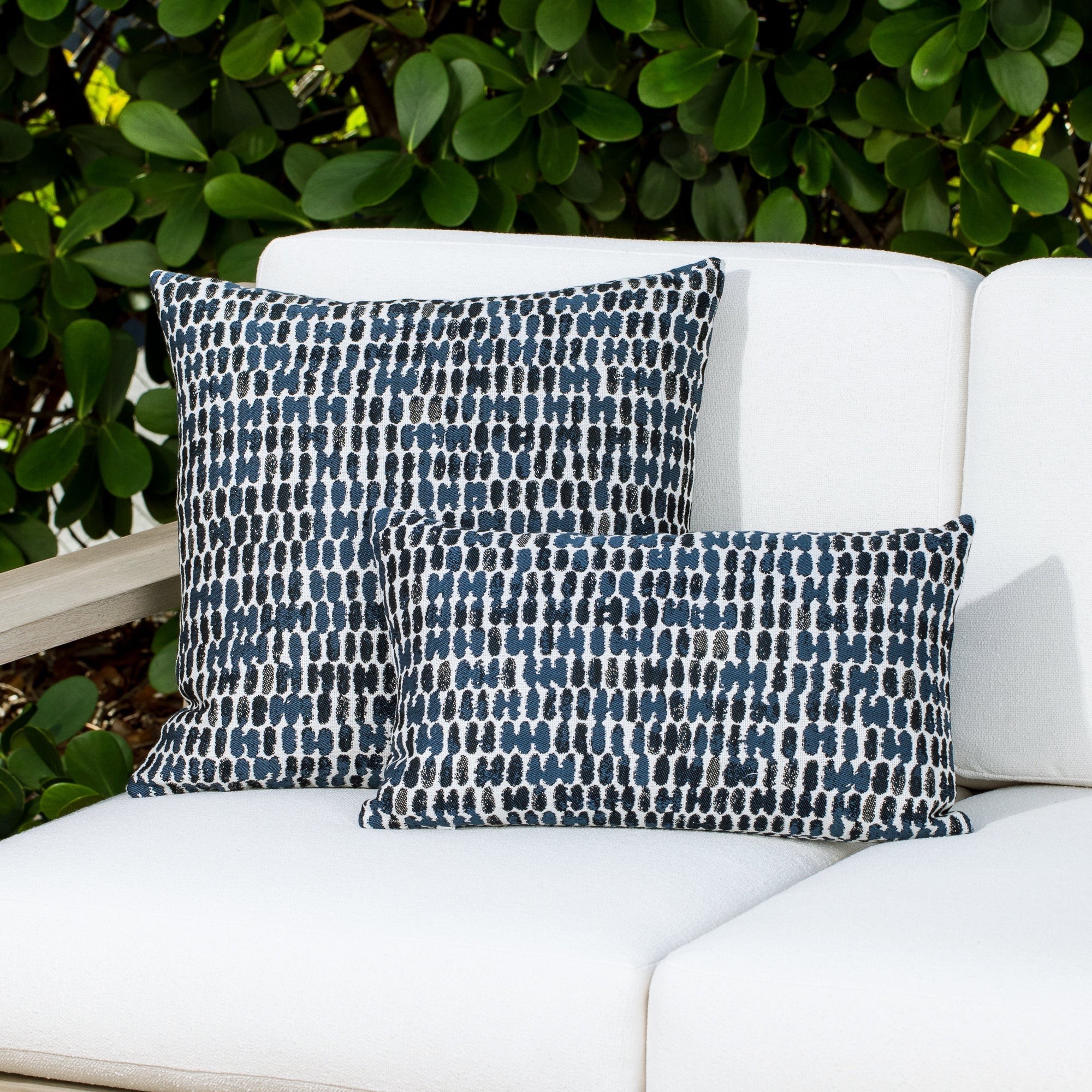 Luxury soft gray botanical patterned bolster pillow on a rooftop seating area, featuring soft touch performance weave for residential and commercial interiors