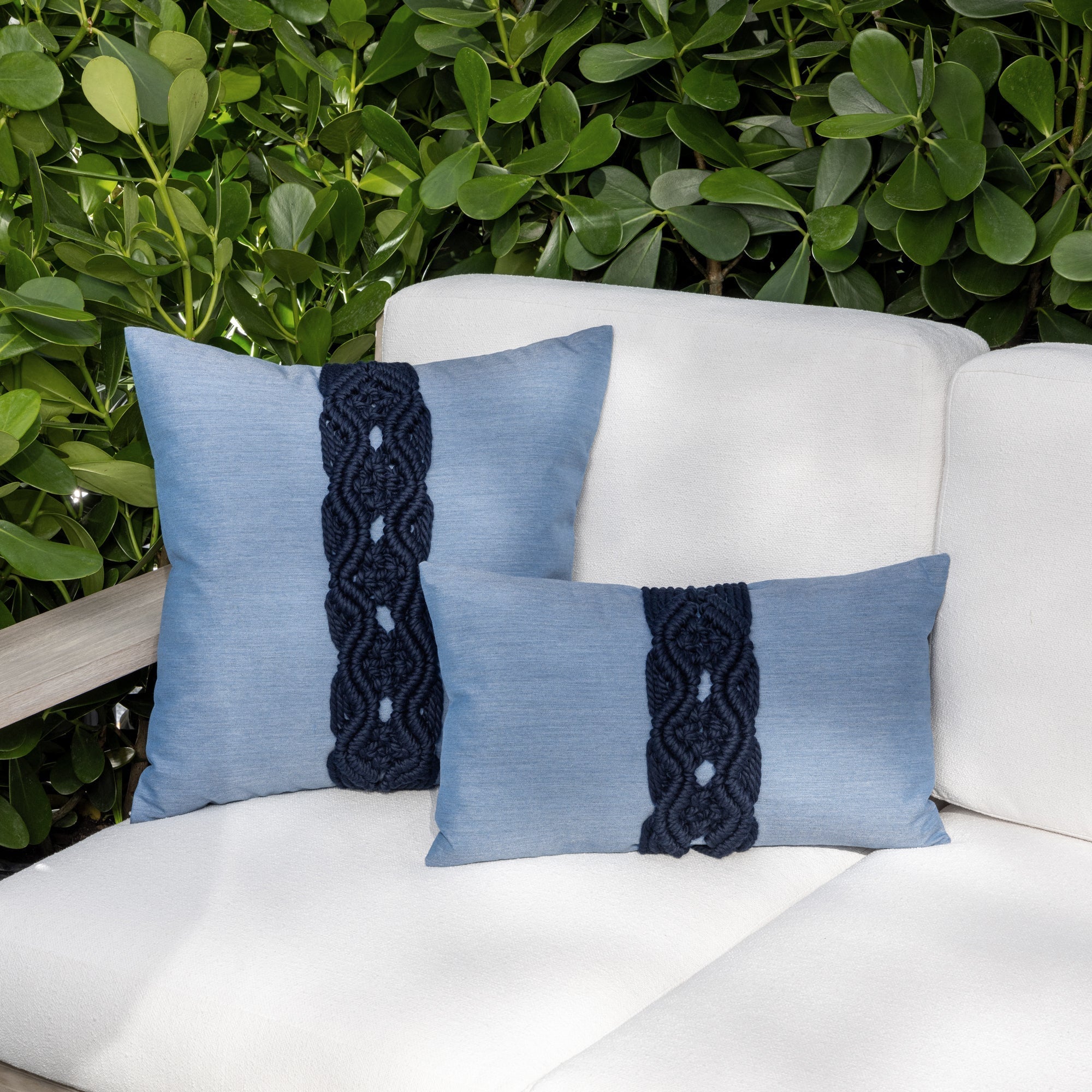Luxury navy blue embroidered throw pillow on an indoor and outdoor sofa, featuring easy clean performance fabric for luxury hotel and resort design by Elaine Smith