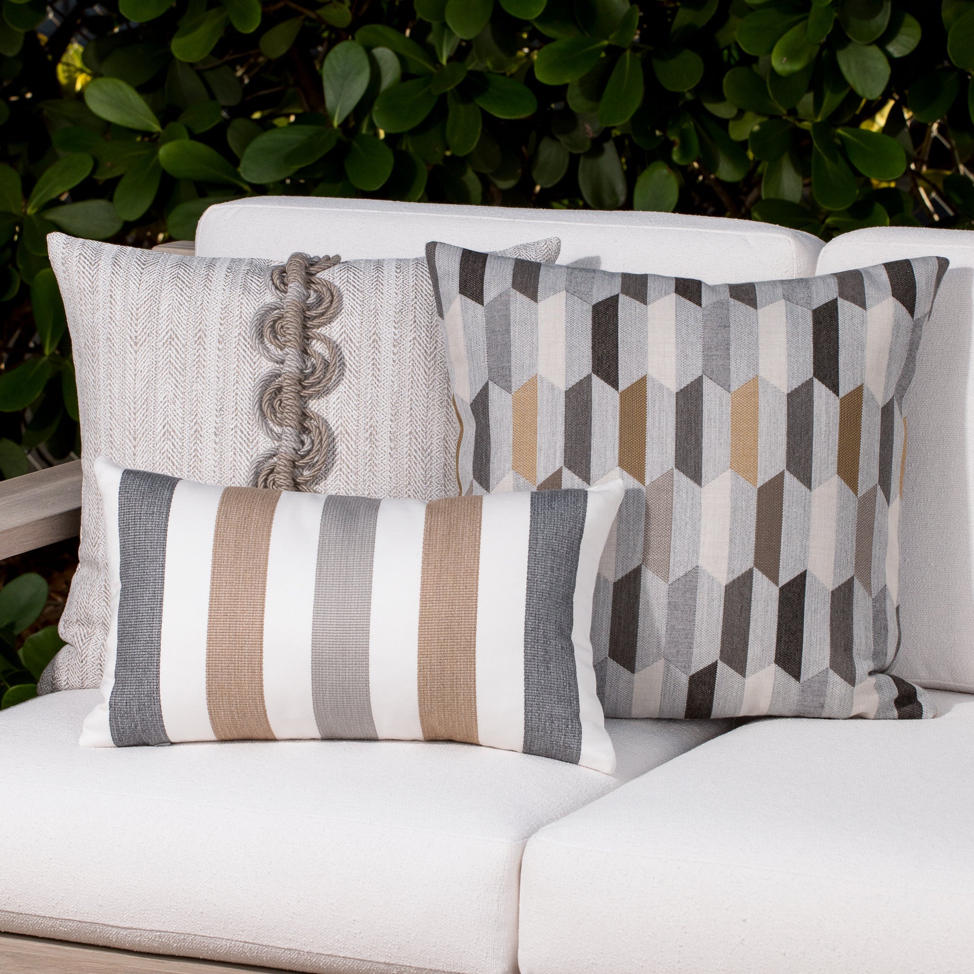 Luxury neutral embroidered accent cushion on a woven lounge chair, featuring rich texture for layered decor for indoor and outdoor use