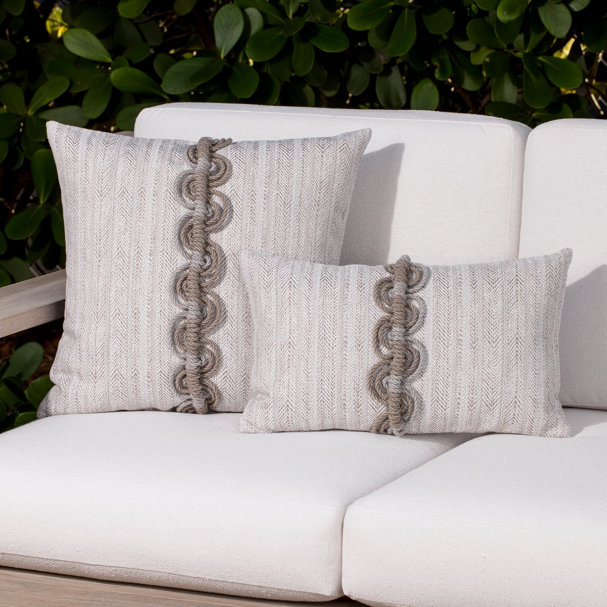 Luxury neutral embroidered accent cushion on a woven lounge chair, featuring rich texture for layered decor for indoor and outdoor use