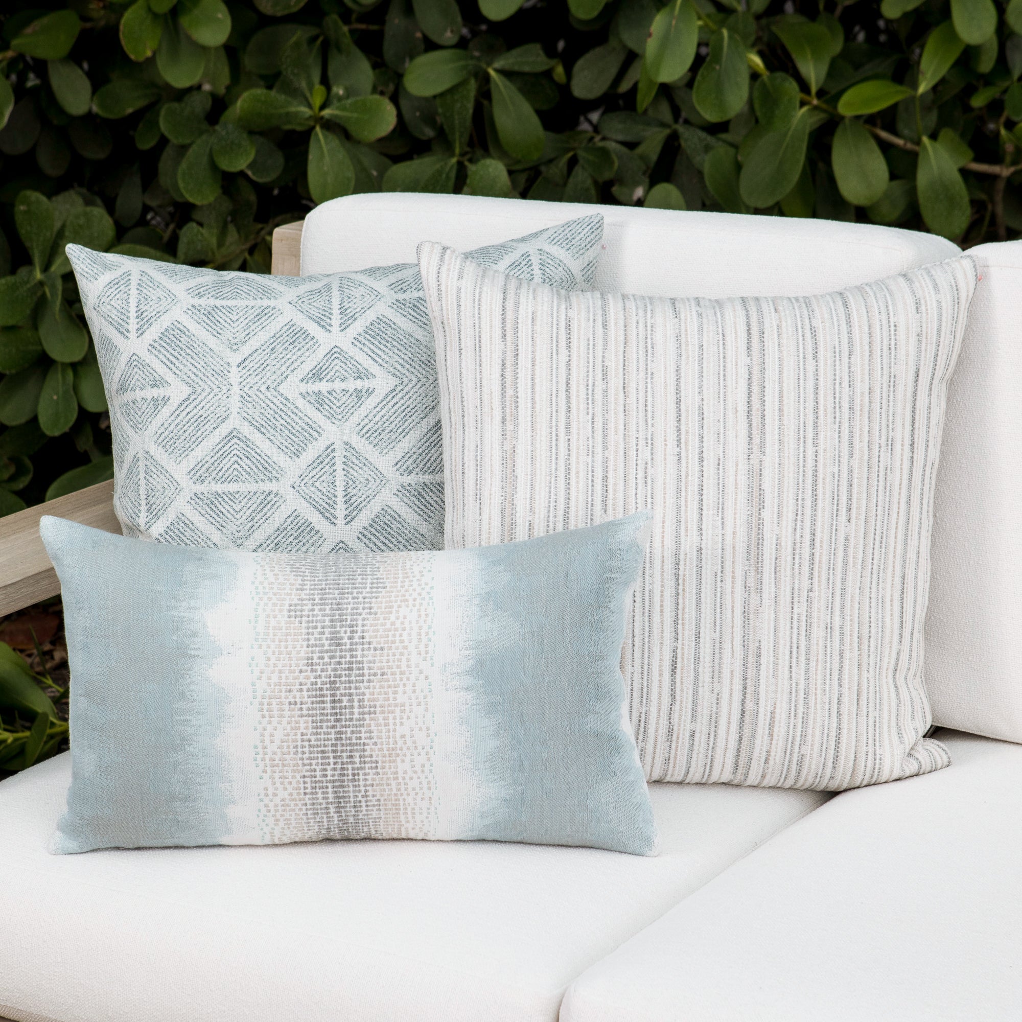 Luxury light blue striped and other soft blue decorative pillows on a outdoor sofa, featuring commercial grade construction for luxury hotel and resort design