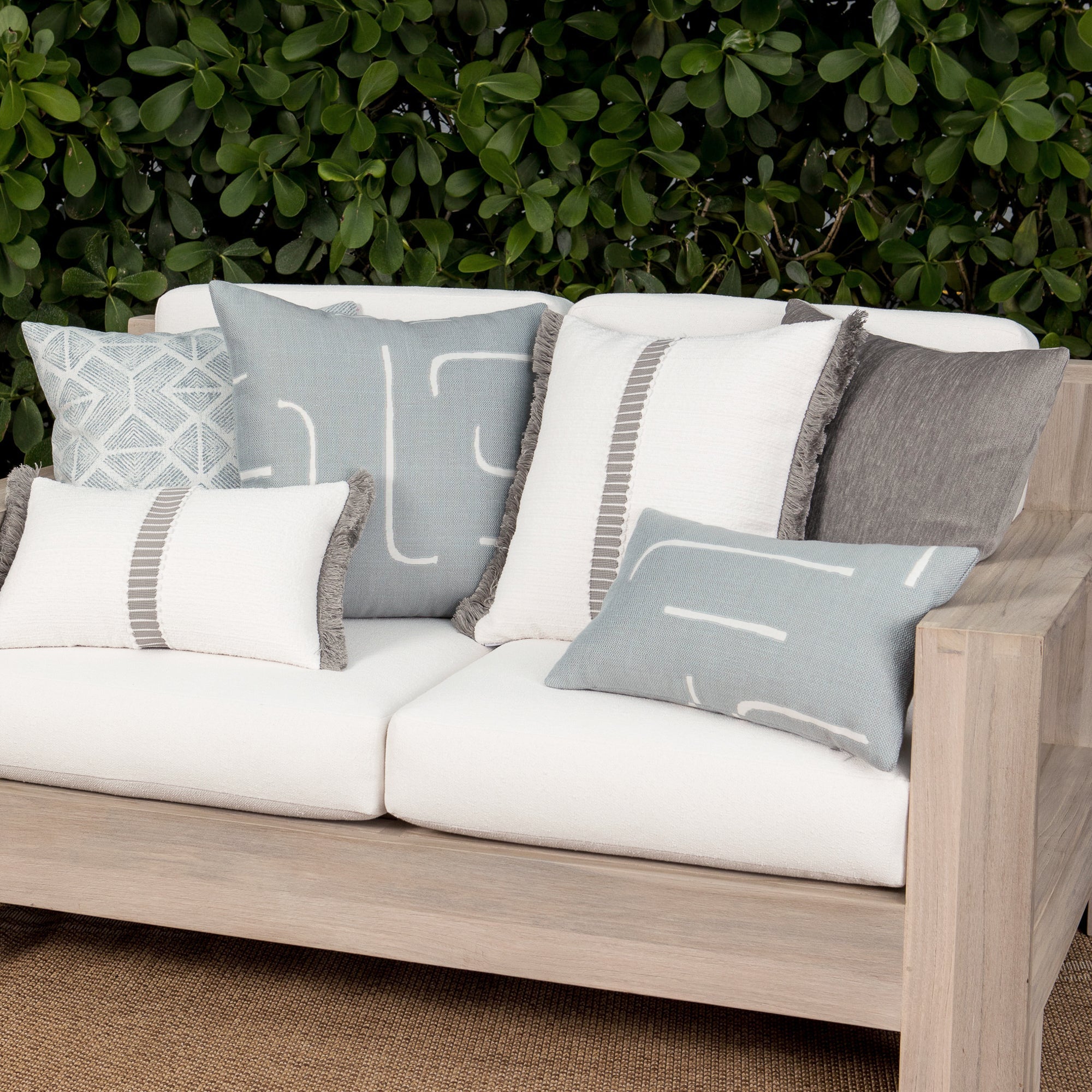 Luxury light blue striped and other soft blue decorative pillows on a outdoor sofa, featuring commercial grade construction for luxury hotel and resort design