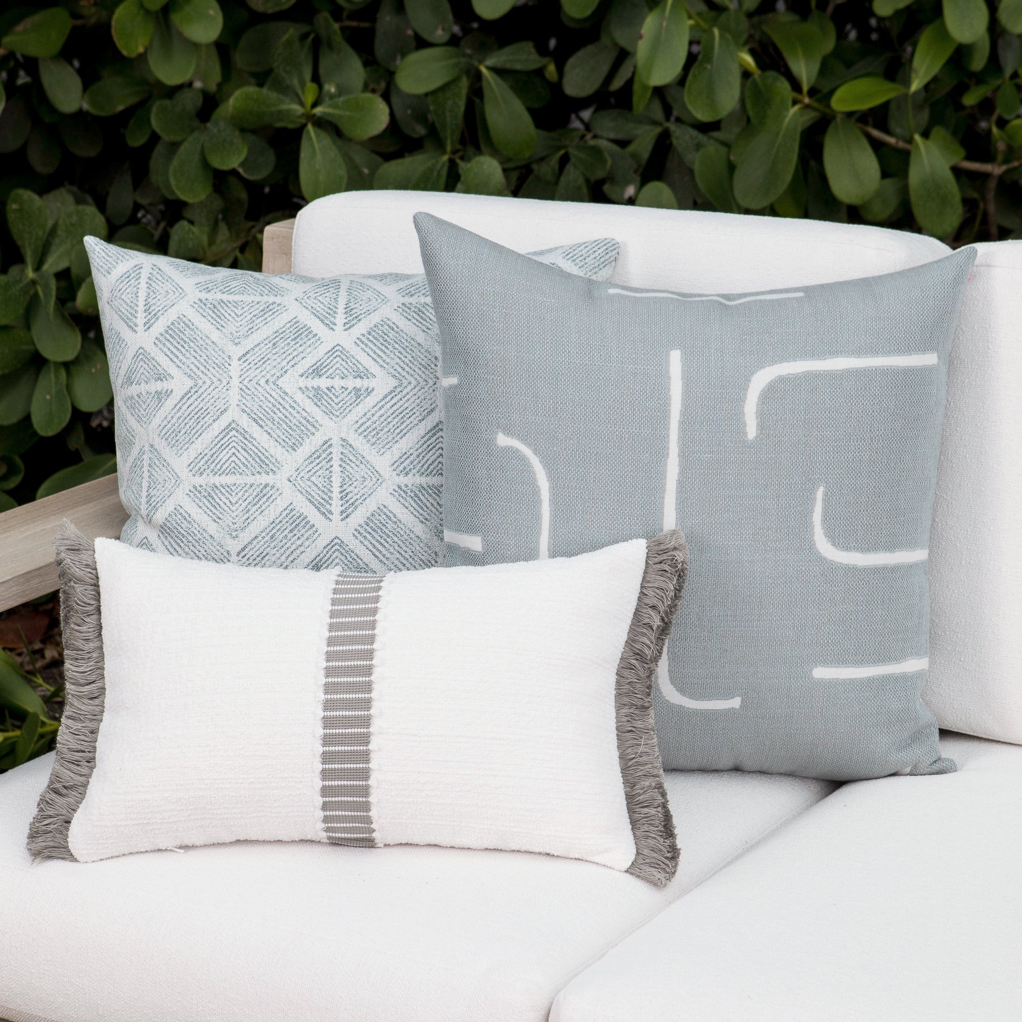 Luxury light blue striped and other soft blue decorative pillows on a outdoor sofa, featuring commercial grade construction for luxury hotel and resort design