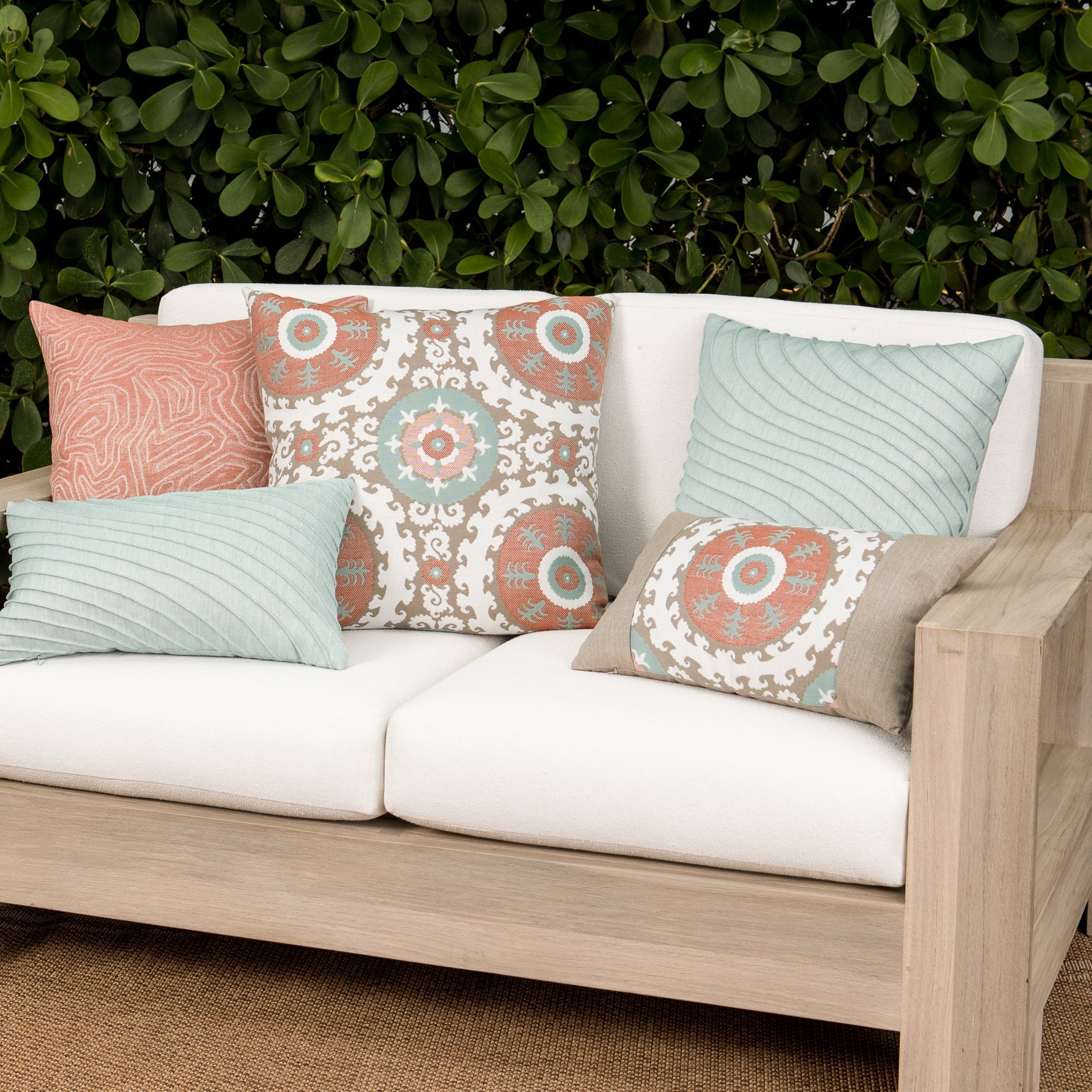 Luxury terracotta tropical leaf patterned accent pillow on an indoor and outdoor sofa, featuring tailored seams for a polished look to complete indoor and outdoor decor by Elaine Smith