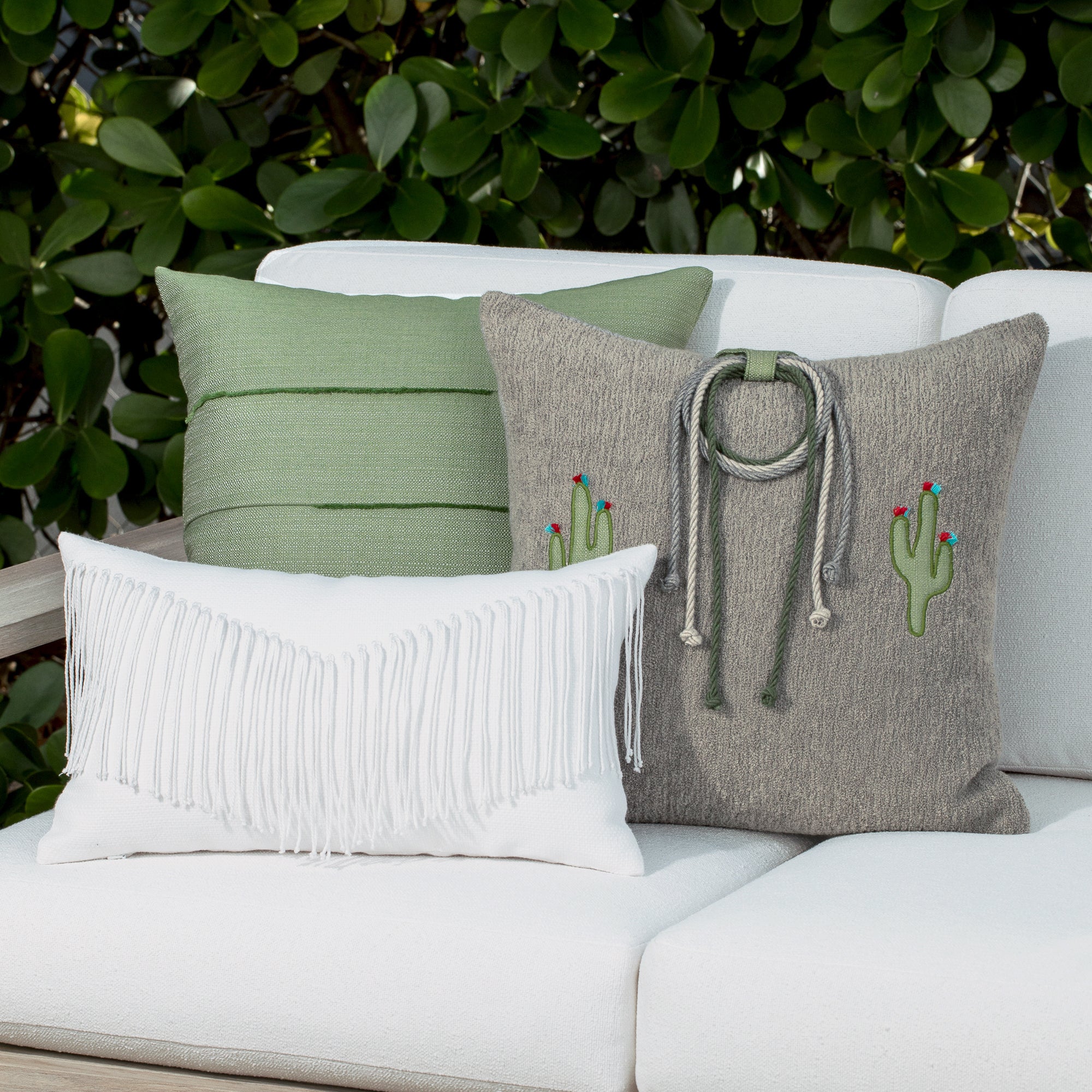 Luxury white modern tassel accent pillow on a outdoor sofa, featuring solution dyed performance fibers for hospitality and commercial spaces