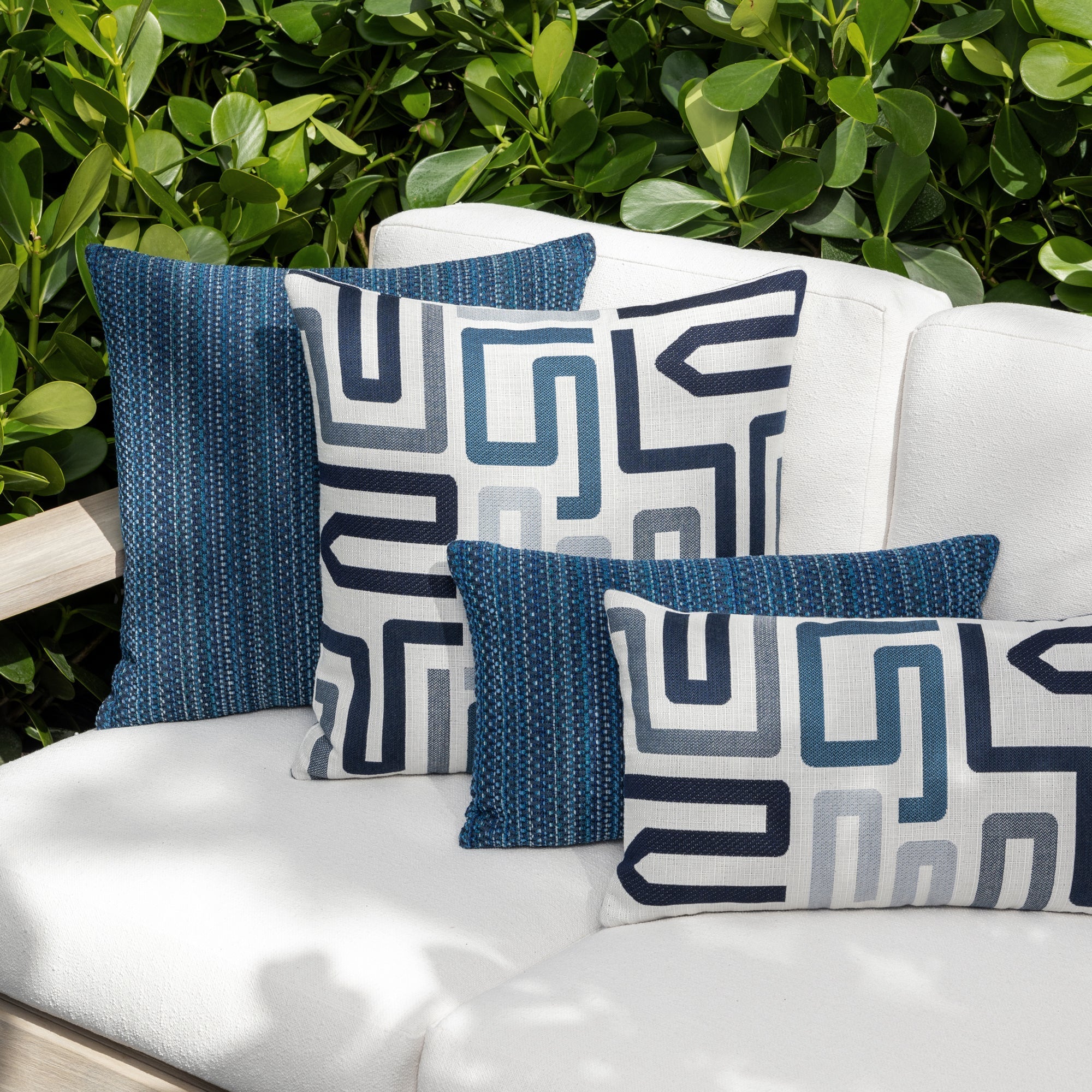 Luxury slate blue textured woven decorative pillow on an indoor and outdoor sofa, featuring commercial grade construction for luxury hotel and resort design