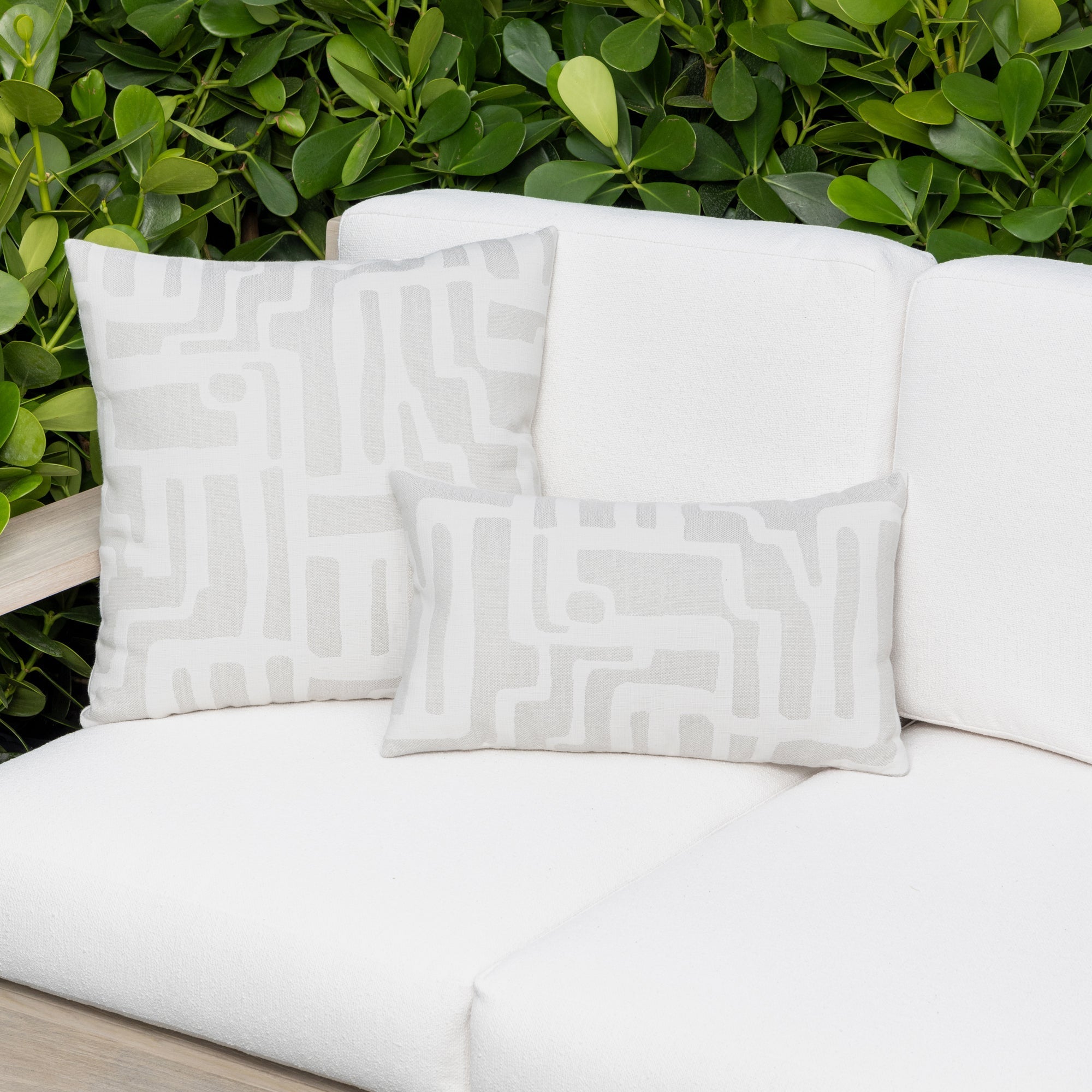 Luxury white textured woven decorative pillow on an indoor and outdoor sofa, featuring commercial grade construction for luxury hotel and resort design