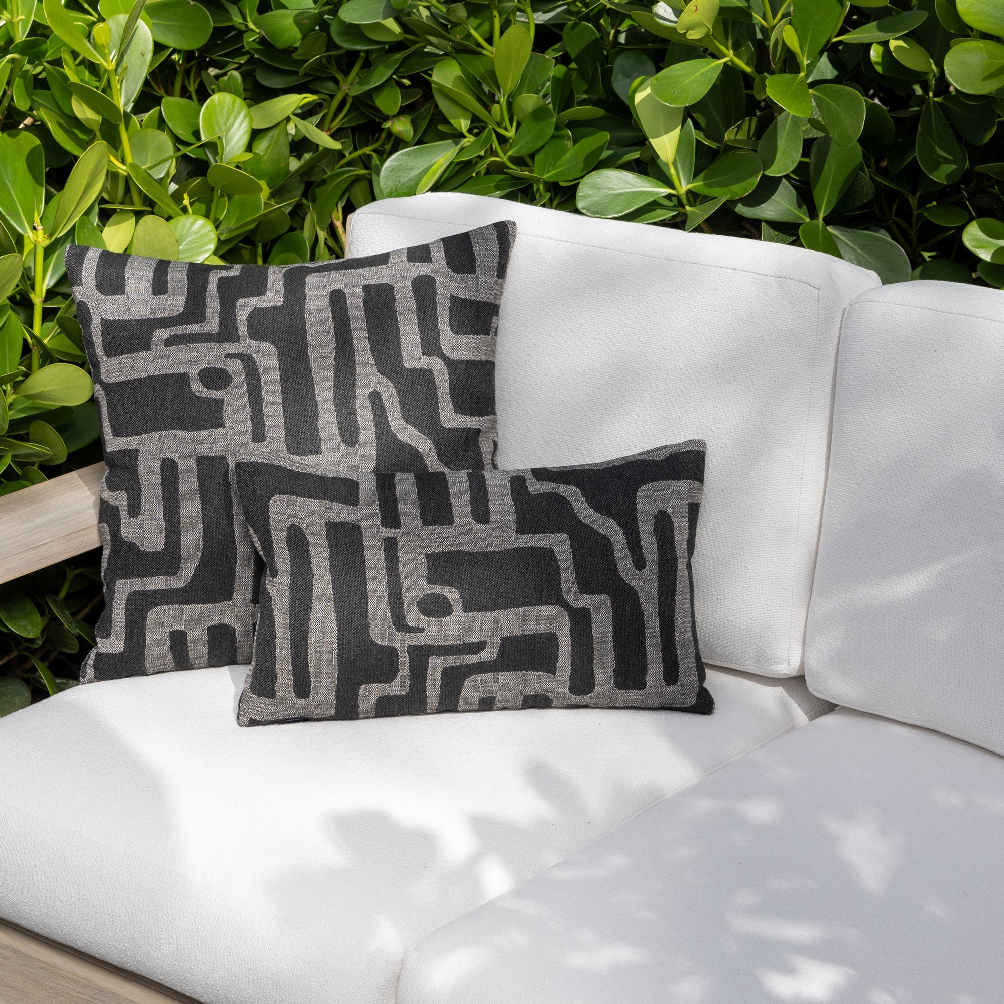 Luxury charcoal gray textured woven decorative pillow on an indoor and outdoor sofa, featuring commercial grade construction for luxury hotel and resort design