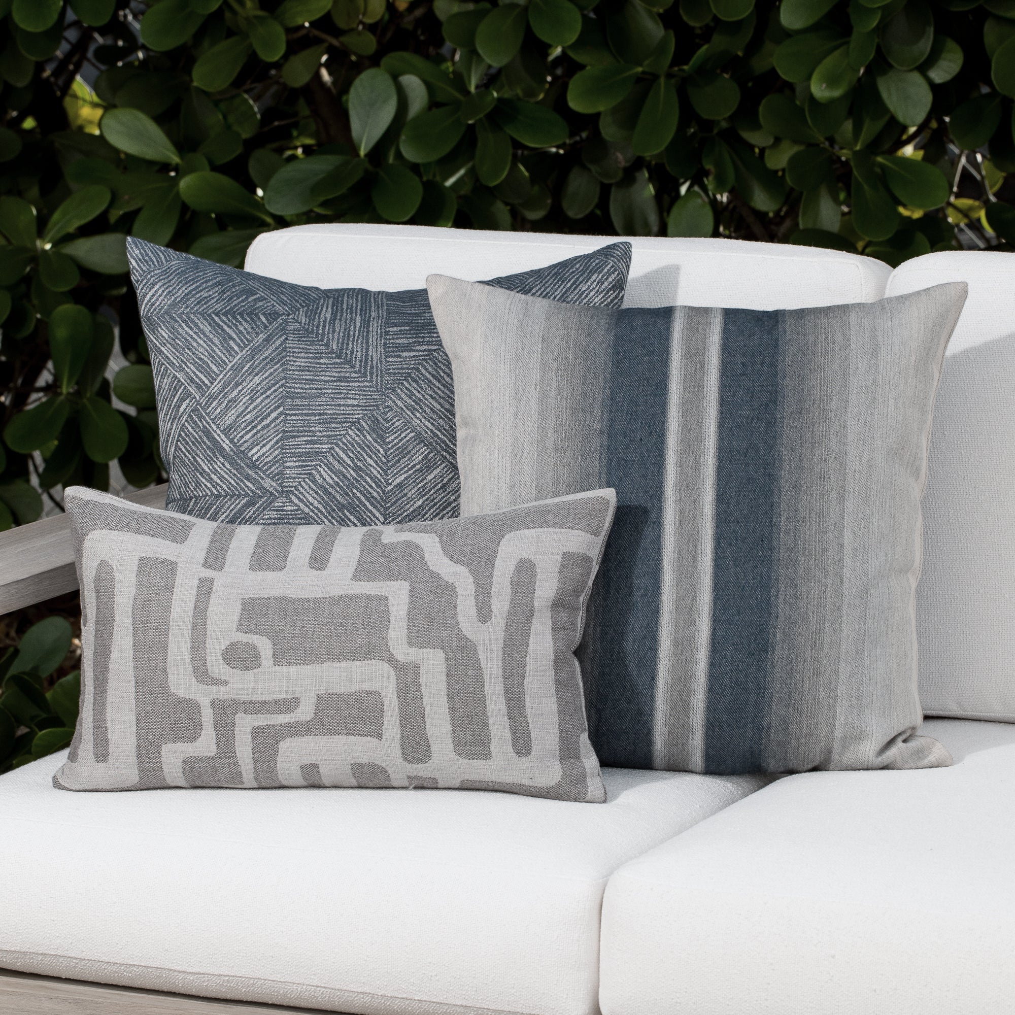 Luxury pewter gray textured woven decorative pillow on an indoor and outdoor sofa, featuring commercial grade construction for luxury hotel and resort design