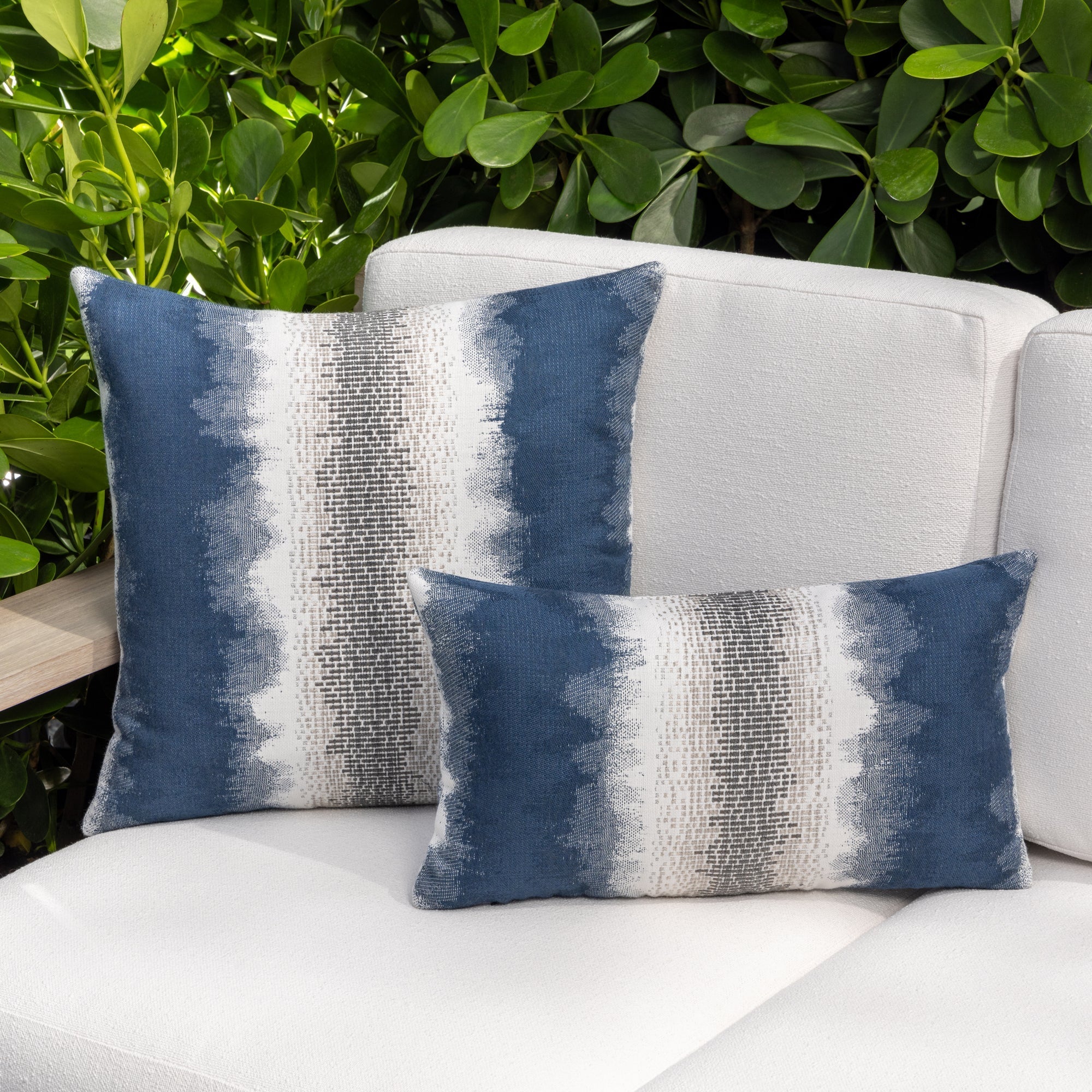 Luxury indigo and white solid throw pillow on an indoor and outdoor sofa, featuring UV and fade resistant fabric to complete indoor and outdoor decor