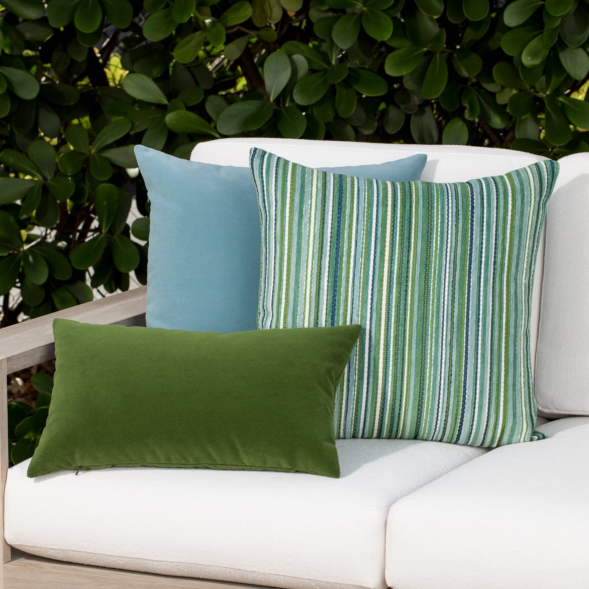 Luxury classic solid velvet pillows on a woven outdoor sofa, featuring rich texture for layered decor for indoor and outdoor use