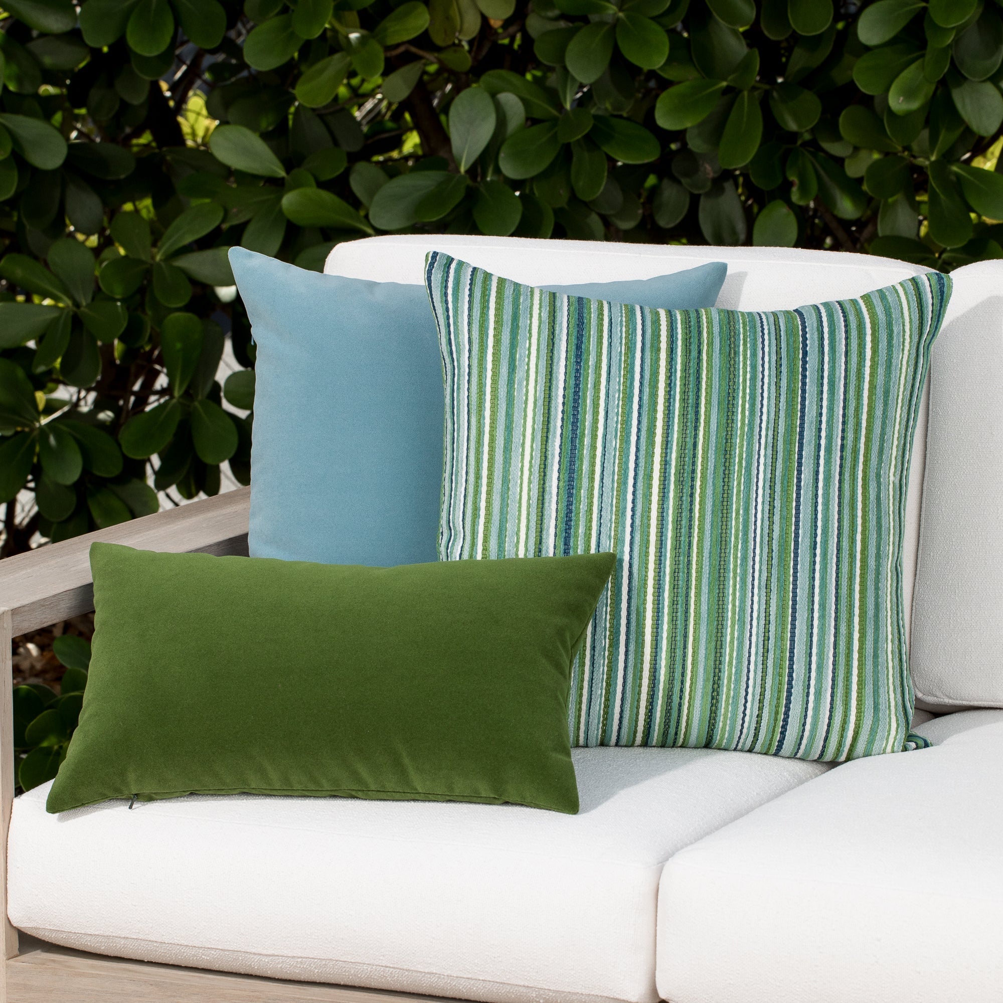 Luxury classic solid velvet pillows on a woven outdoor sofa, featuring rich texture for layered decor for indoor and outdoor use