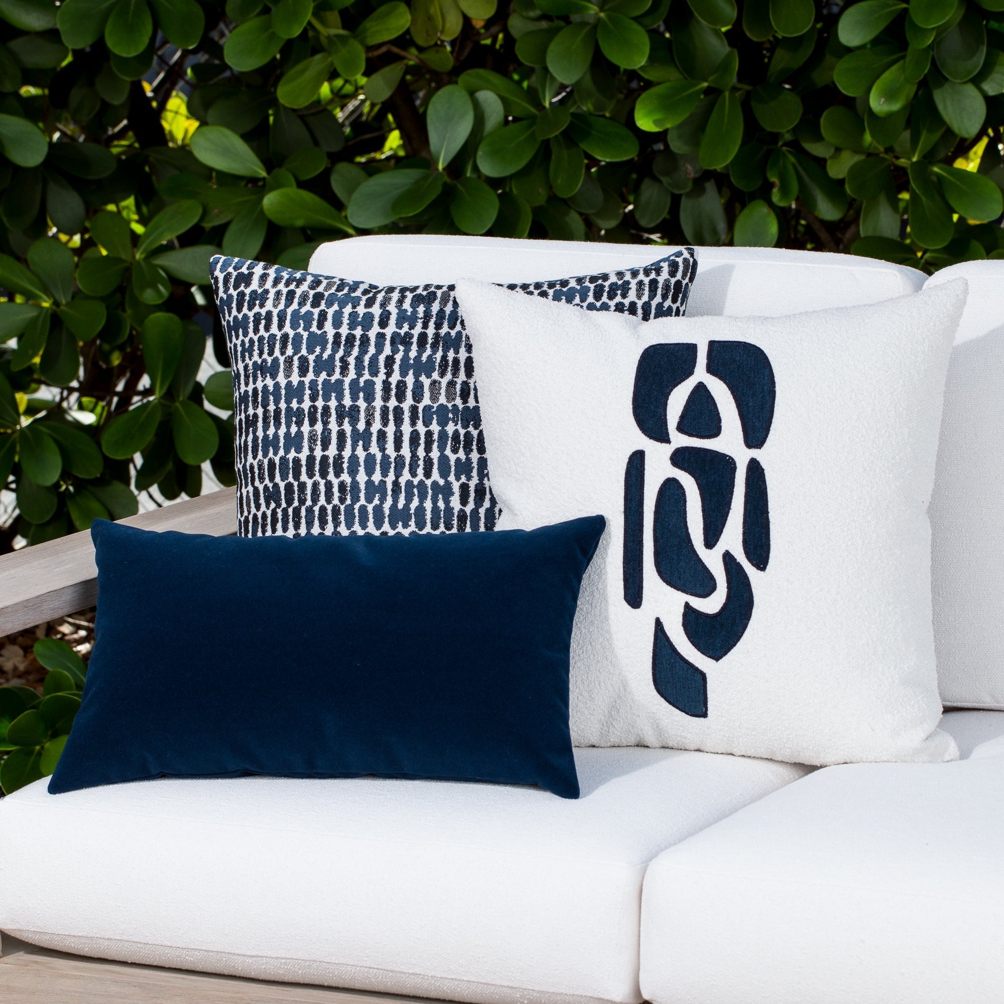 Luxury classic solid velvet pillows on a woven outdoor sofa, featuring rich texture for layered decor for indoor and outdoor use