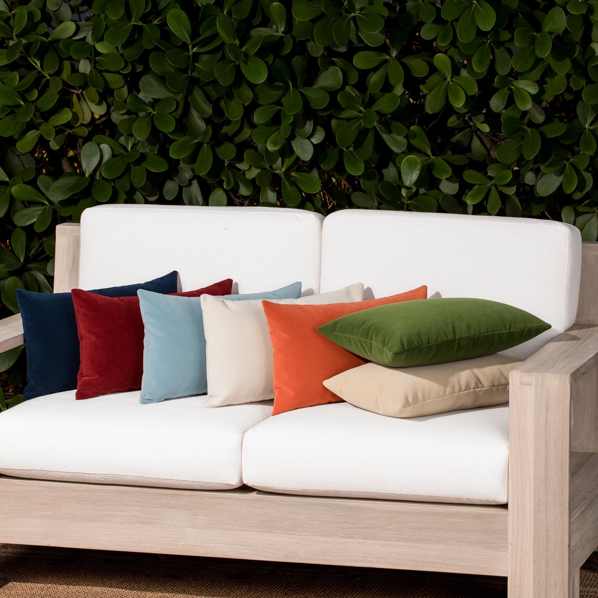 Luxury classic solid velvet pillows on a woven outdoor sofa, featuring rich texture for layered decor for indoor and outdoor use