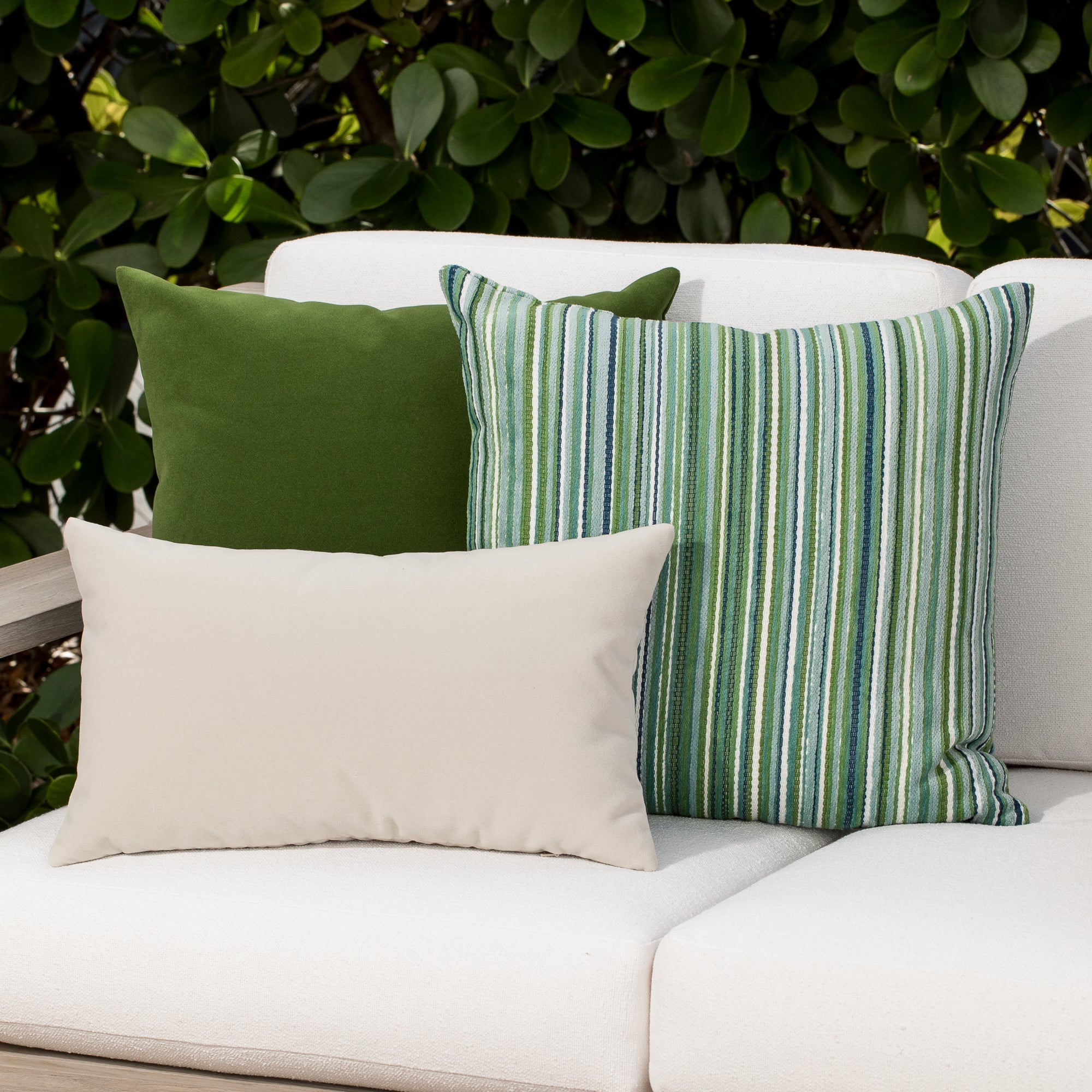 Luxury classic solid velvet pillows on a woven outdoor sofa, featuring rich texture for layered decor for indoor and outdoor use