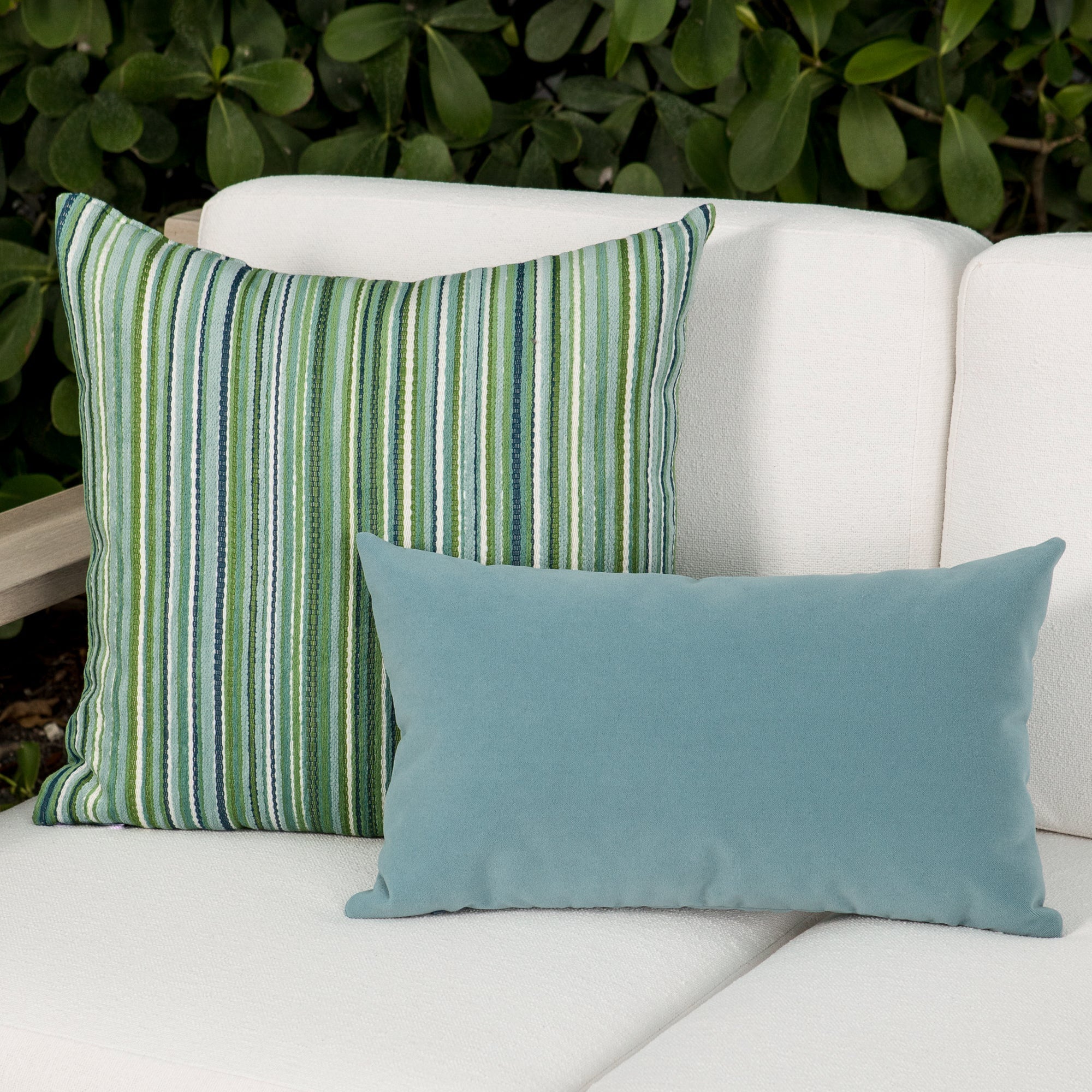 Luxury classic solid velvet pillows on a woven outdoor sofa, featuring rich texture for layered decor for indoor and outdoor use