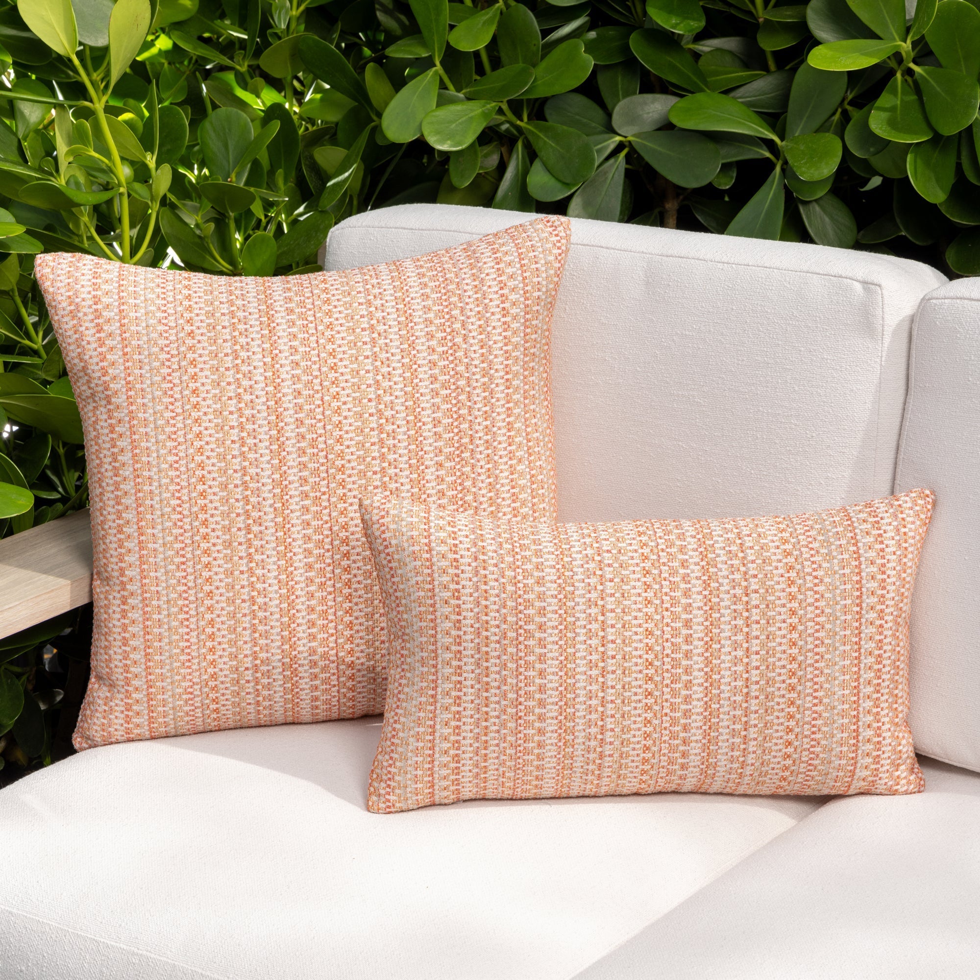 Luxury clay colored subtle patterned accent pillow on a outdoor sofa styled for hospitality suites, featuring rich texture for layered decor for indoor and outdoor use