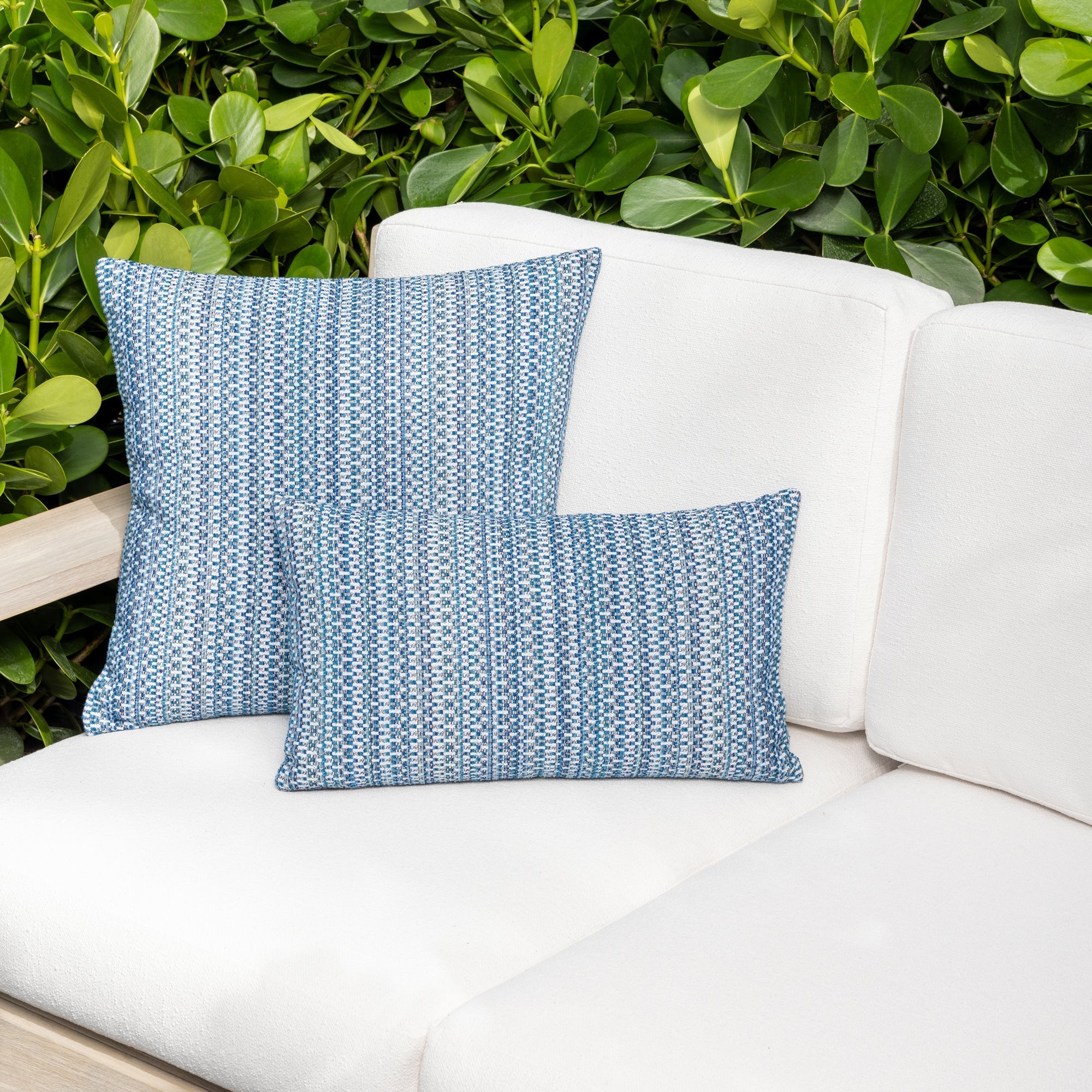 Luxury indigo colored subtle patterned accent pillow on a outdoor sofa styled for hospitality suites, featuring rich texture for layered decor for indoor and outdoor use