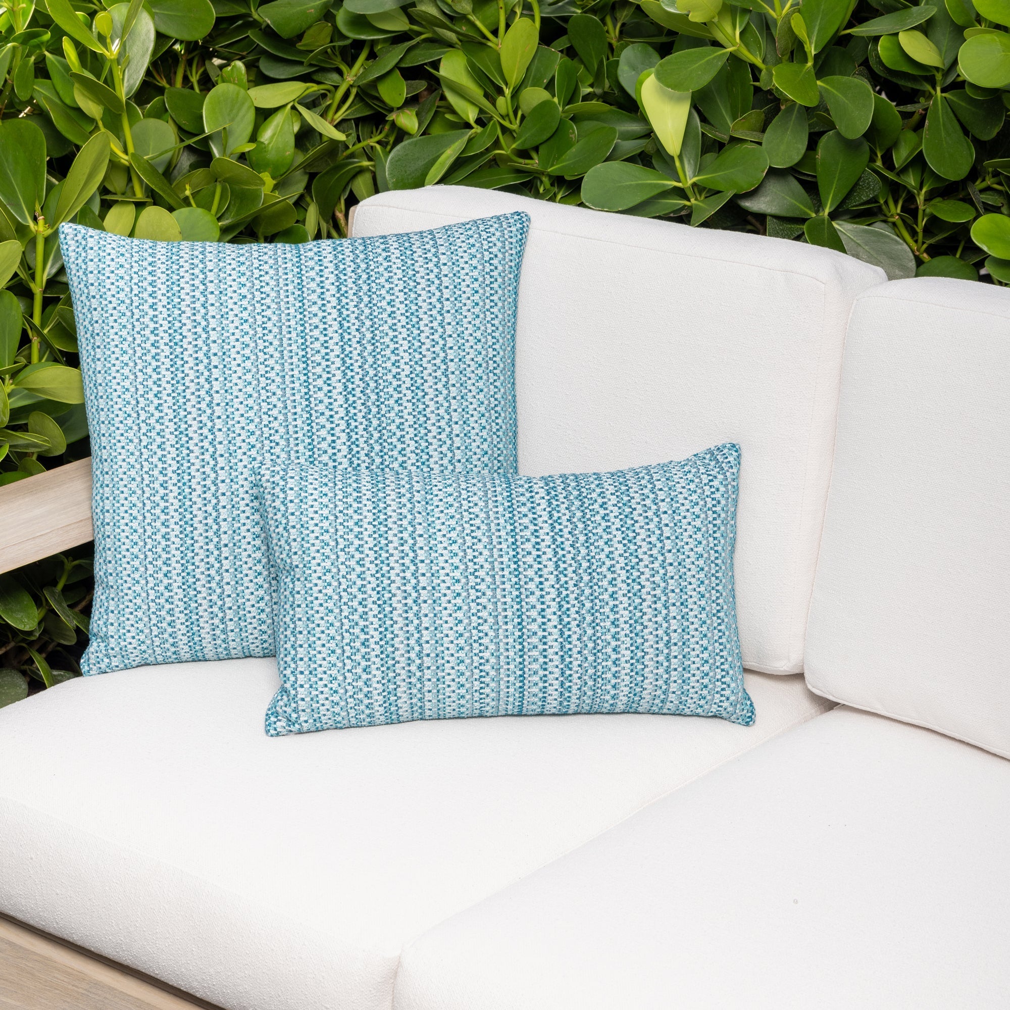 Luxury lagoon colored subtle patterned accent pillow on a outdoor sofa styled for hospitality suites, featuring rich texture for layered decor for indoor and outdoor use