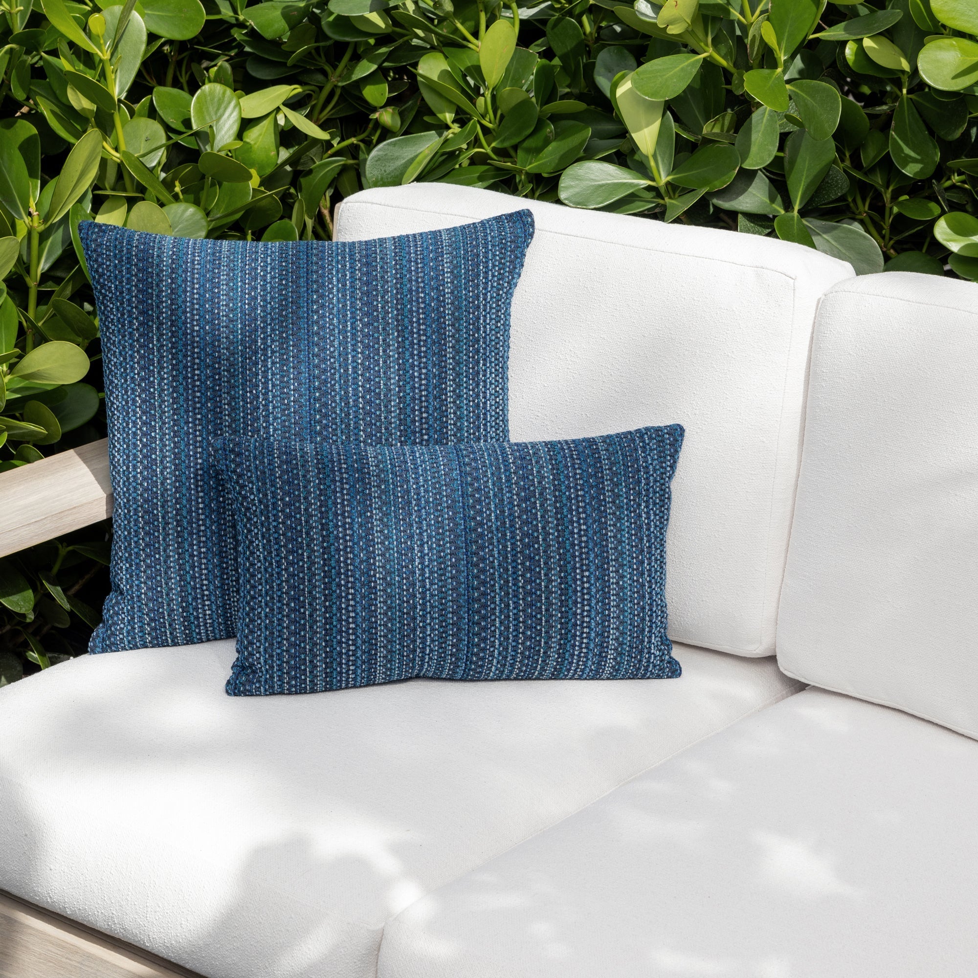 Luxury midnight blue colored subtle patterned accent pillow on a outdoor sofa styled for hospitality suites, featuring rich texture for layered decor for indoor and outdoor use