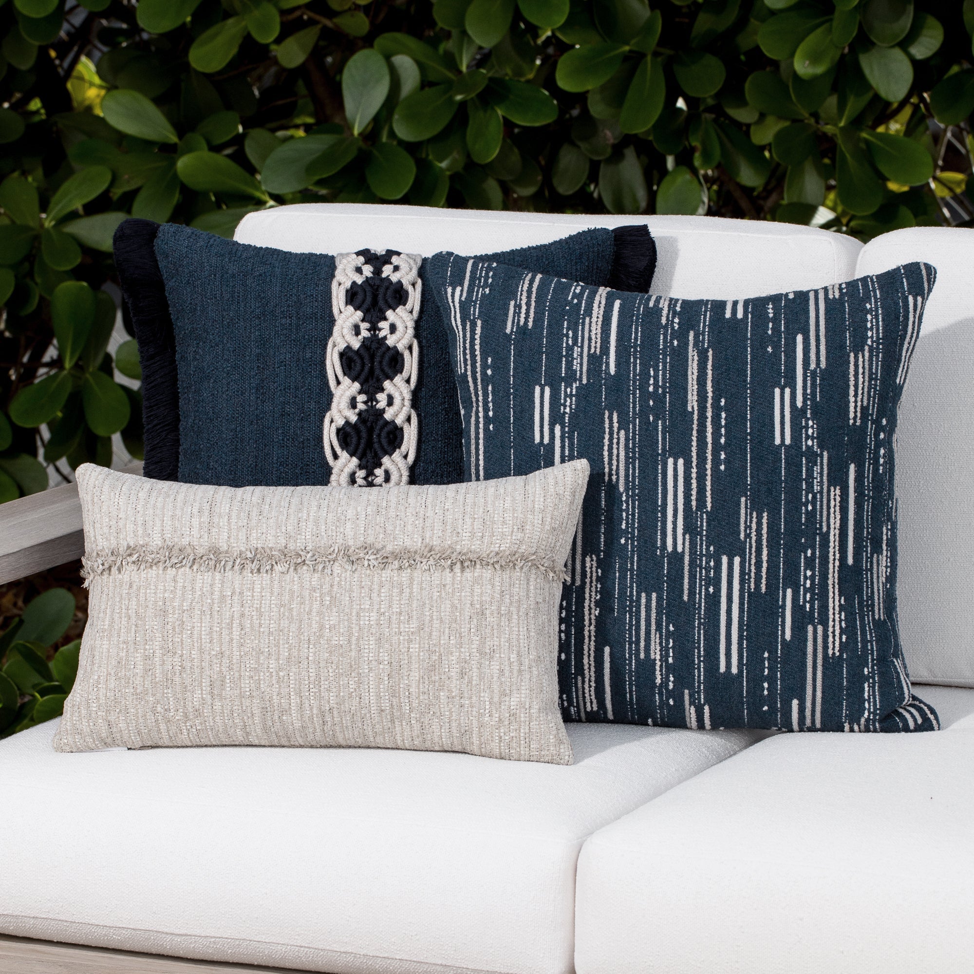 Luxury navy blue botanical patterned and neutral accent pillow on a outdoor sofa, featuring easy clean performance fabric for luxury hotel and resort design by Elaine Smith