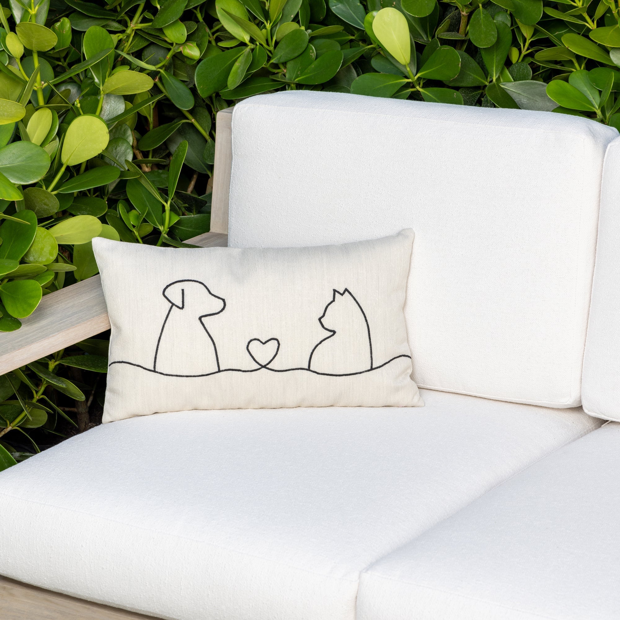 Luxury ivory throw pillow with stitching in a dog and cat shape on a outdoor sofa, featuring rich texture for layered decor for indoor and outdoor use