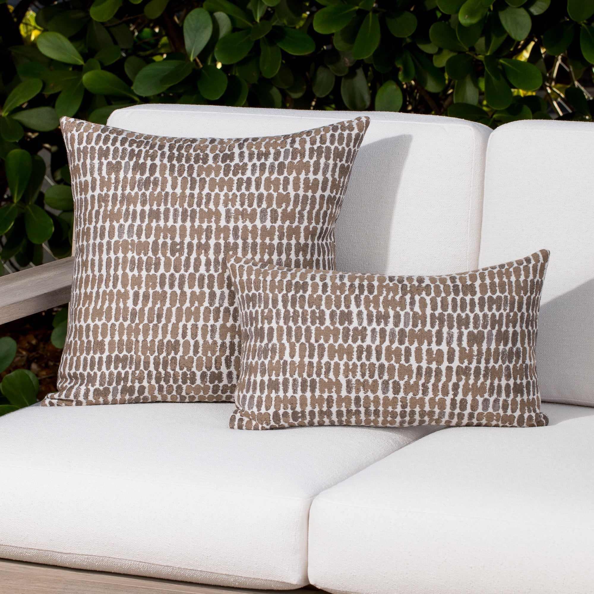 Luxury taupe and white two tone cushion on a woven outdoor sofa, featuring commercial grade construction for luxury hotel and resort design
