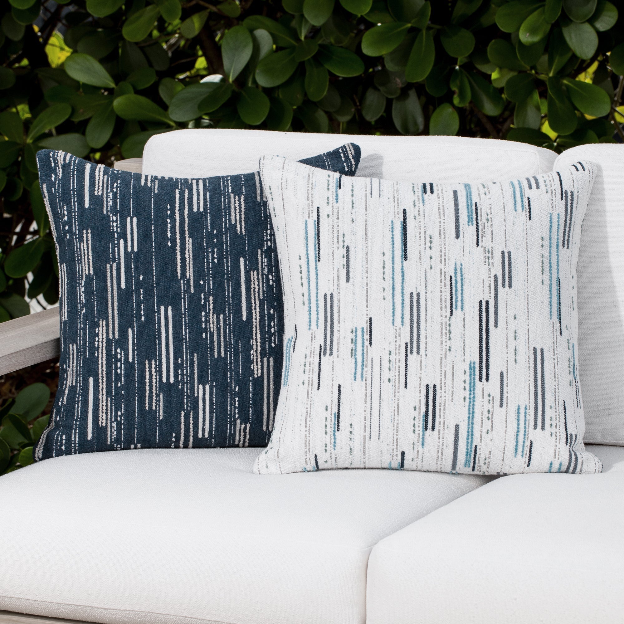 Luxury indigo and beige geometric patterned accent pillow on a outdoor sofa, featuring all weather performance construction for residential and commercial interiors