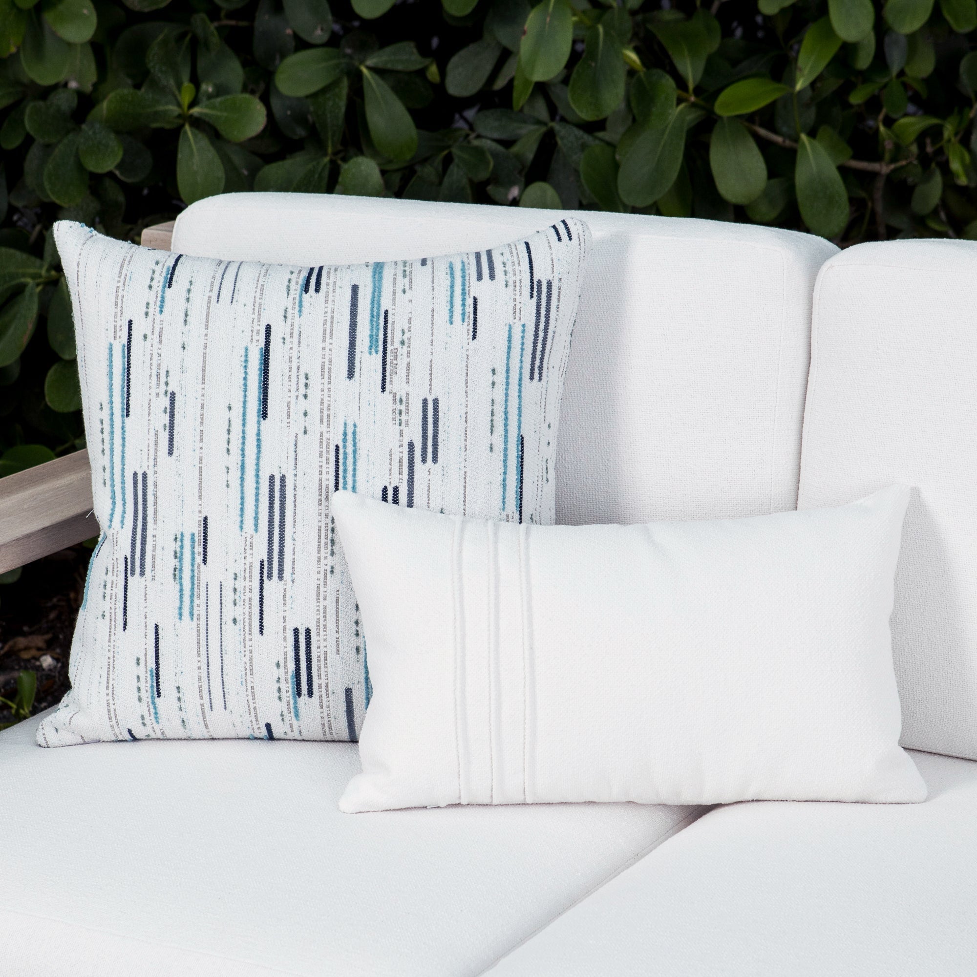 Luxury indigo and beige geometric patterned accent pillow on a outdoor sofa, featuring all weather performance construction for residential and commercial interiors