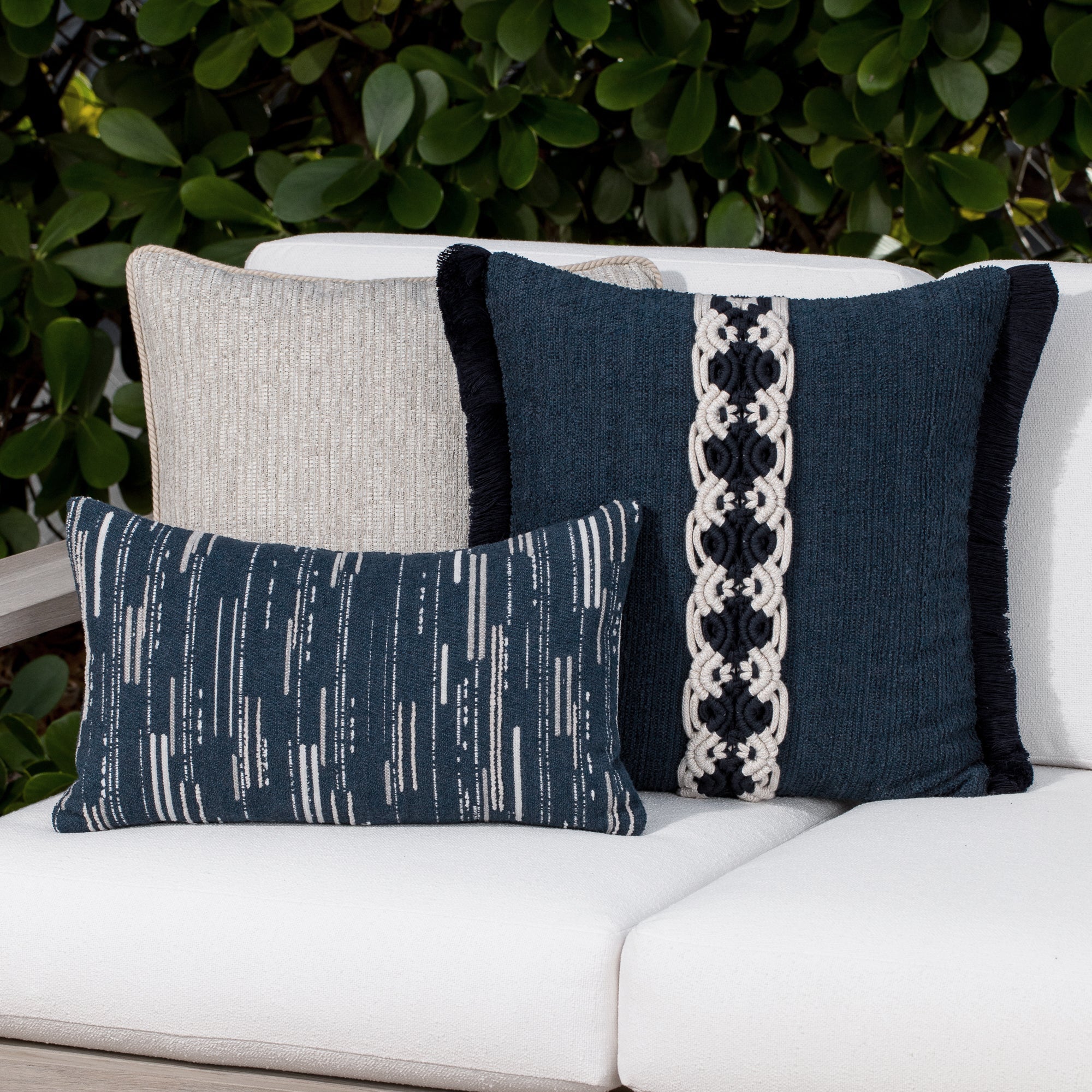 Luxury indigo and beige geometric patterned accent pillow on a outdoor sofa, featuring all weather performance construction for residential and commercial interiors