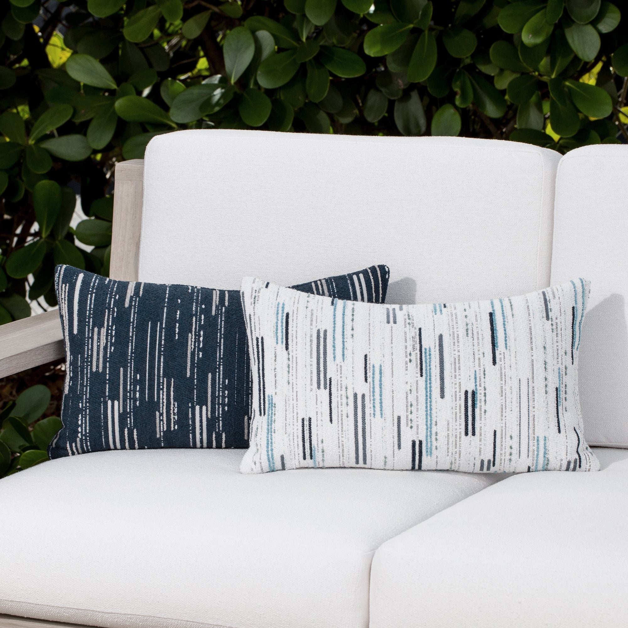 Luxury indigo and beige geometric patterned accent pillow on a outdoor sofa, featuring all weather performance construction for residential and commercial interiors