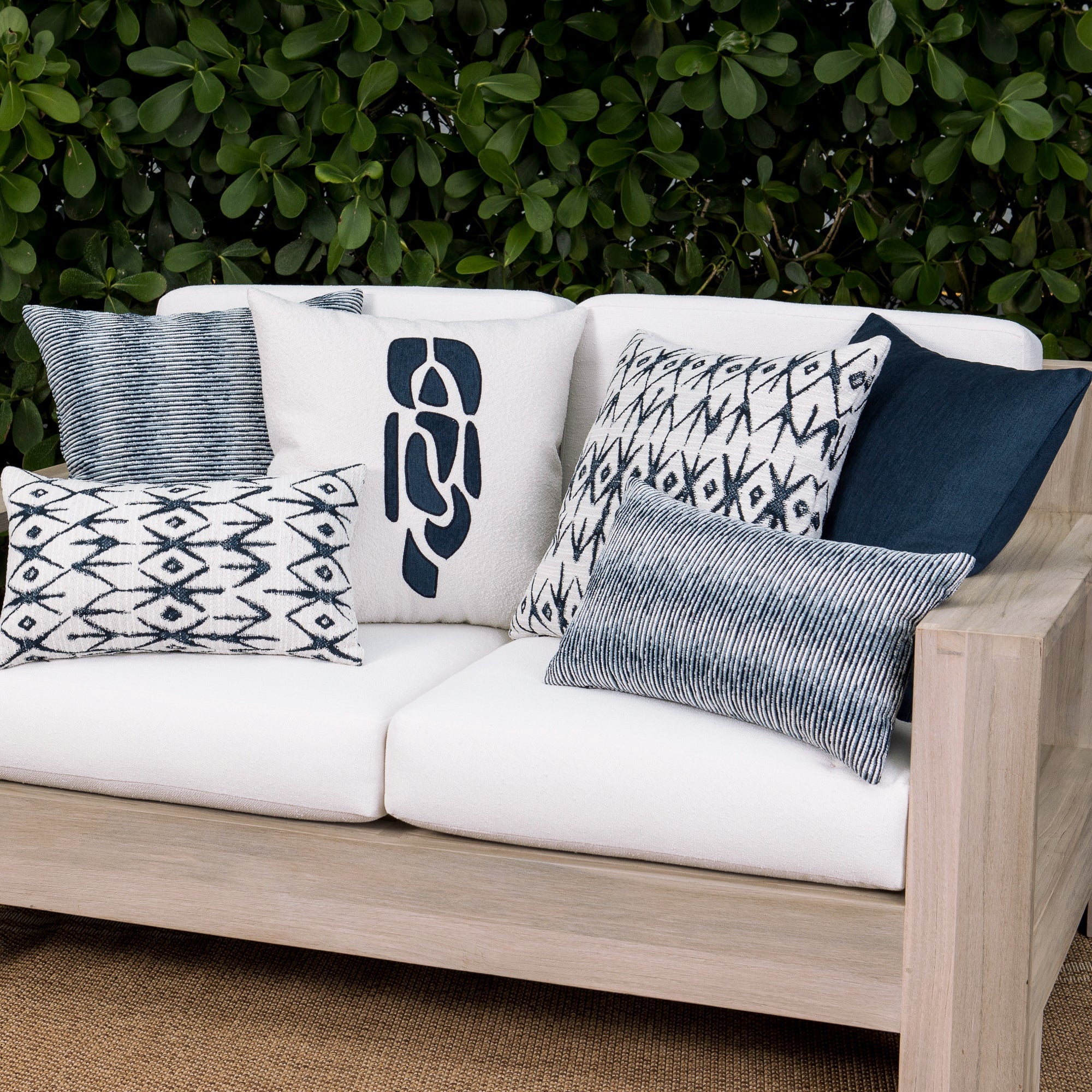 Luxury indigo subtle patterned decorative pillow on a woven outdoor sofa, featuring soft touch performance weave for residential and commercial interiors