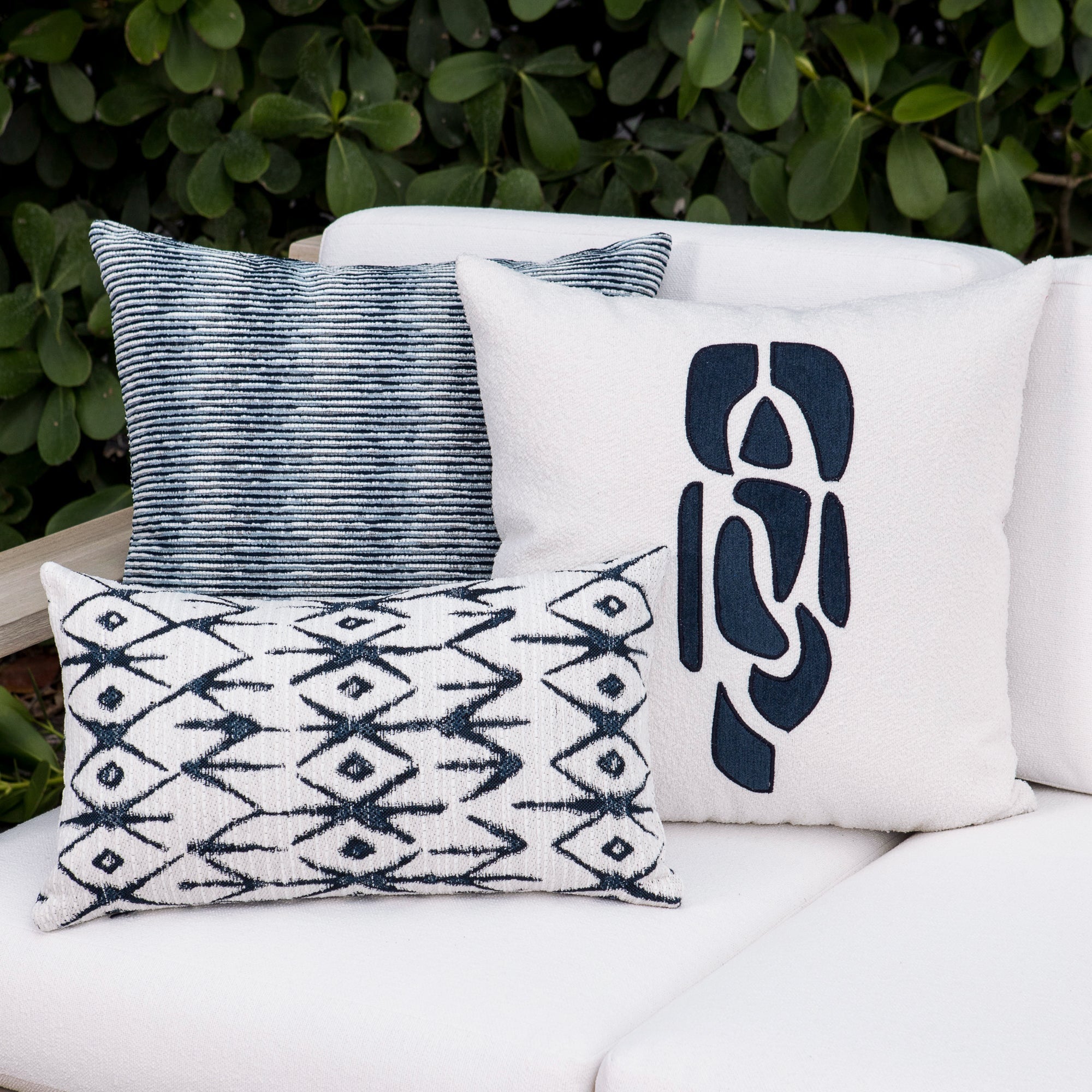 Luxury indigo subtle patterned decorative pillow on a woven outdoor sofa, featuring soft touch performance weave for residential and commercial interiors