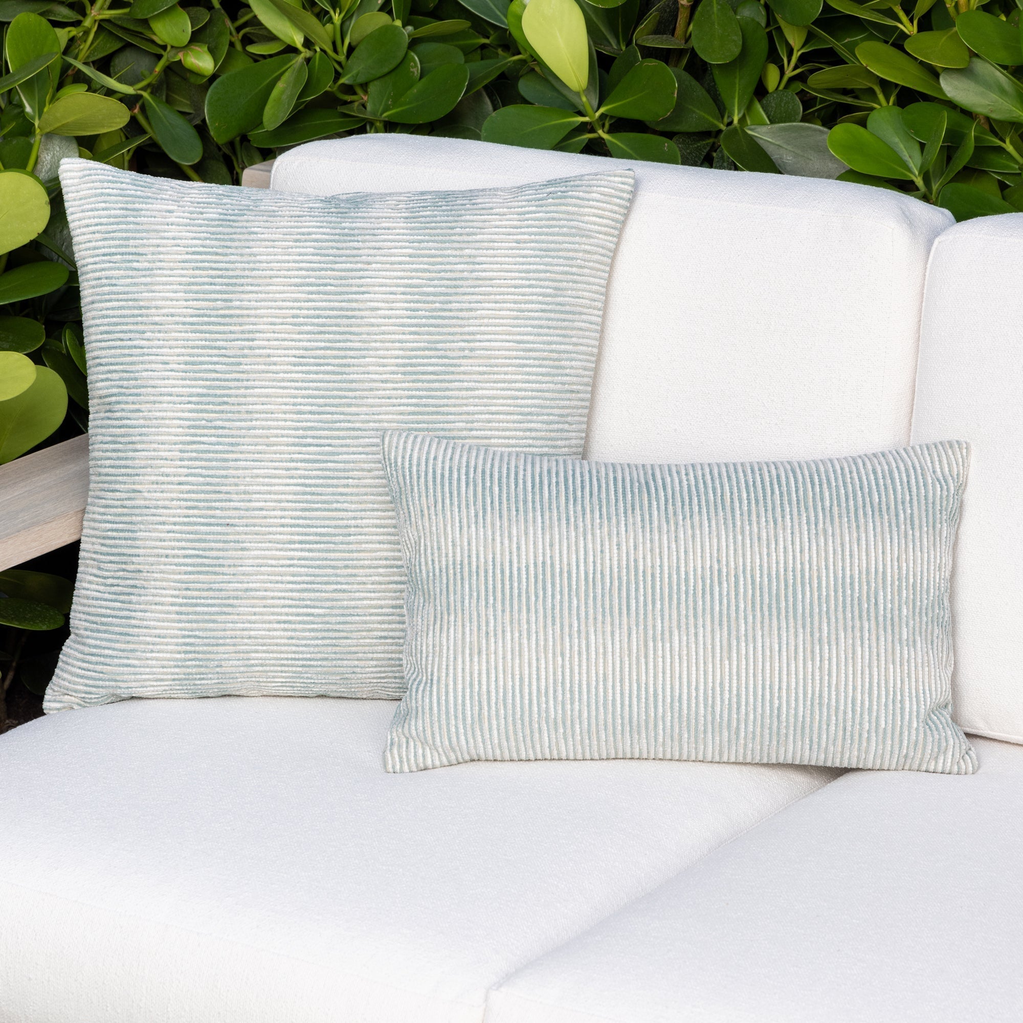 Luxury light blue subtle patterned decorative pillow on a woven outdoor sofa, featuring soft touch performance weave for residential and commercial interiors