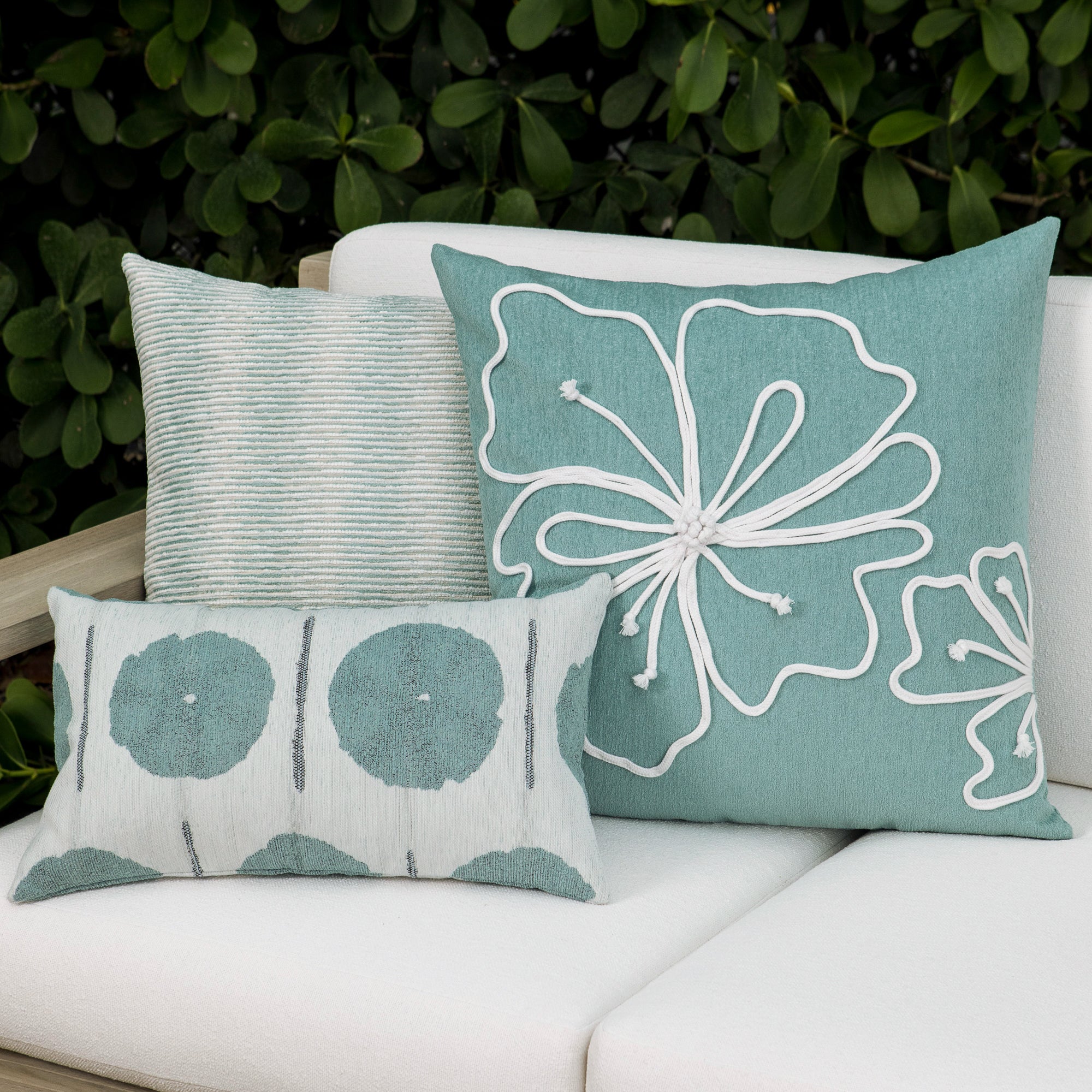 Luxury light blue subtle patterned decorative pillow on a woven outdoor sofa, featuring soft touch performance weave for residential and commercial interiors