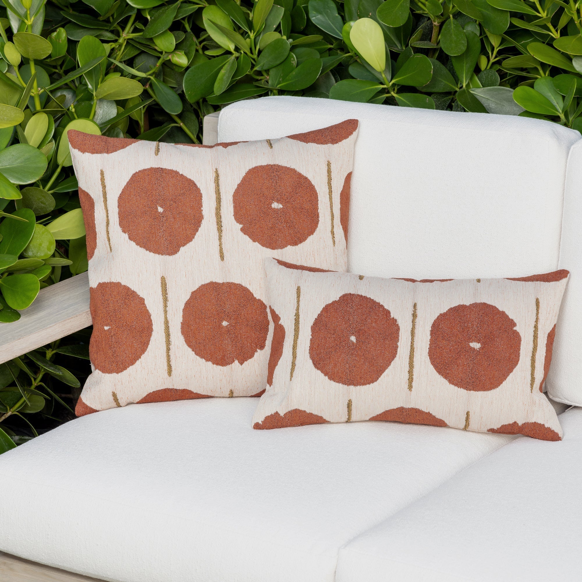 Luxury rust and cream geometric patterned accent pillow on a outdoor sofa, featuring commercial grade construction for luxury hotel and resort design